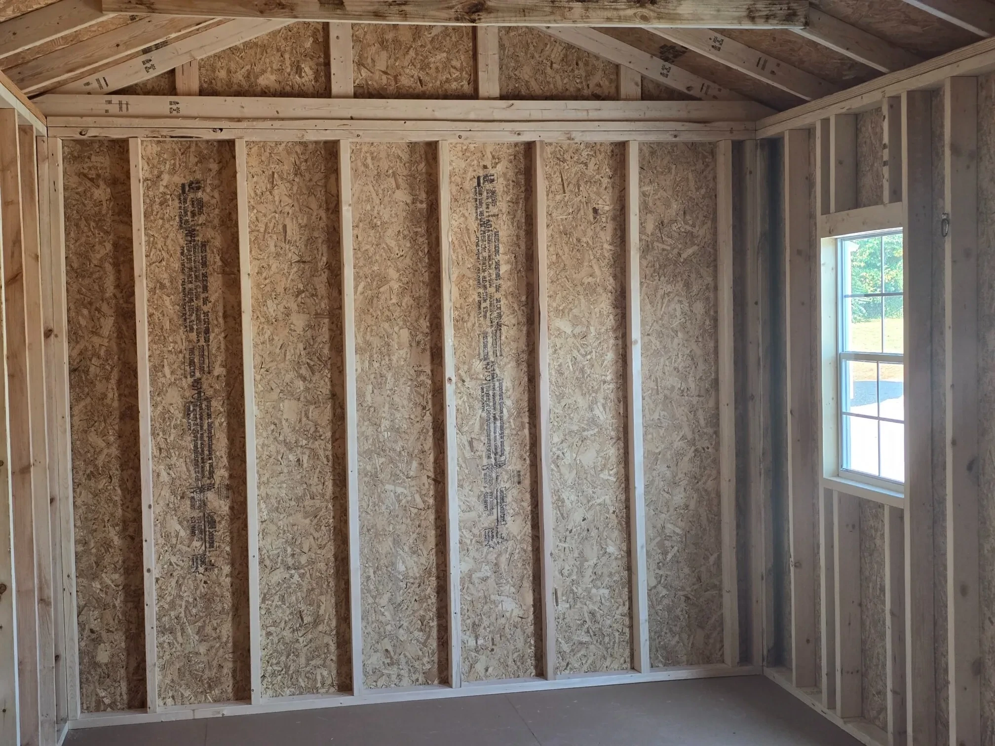 inside a wood garden shed with a window and sunshine coming through