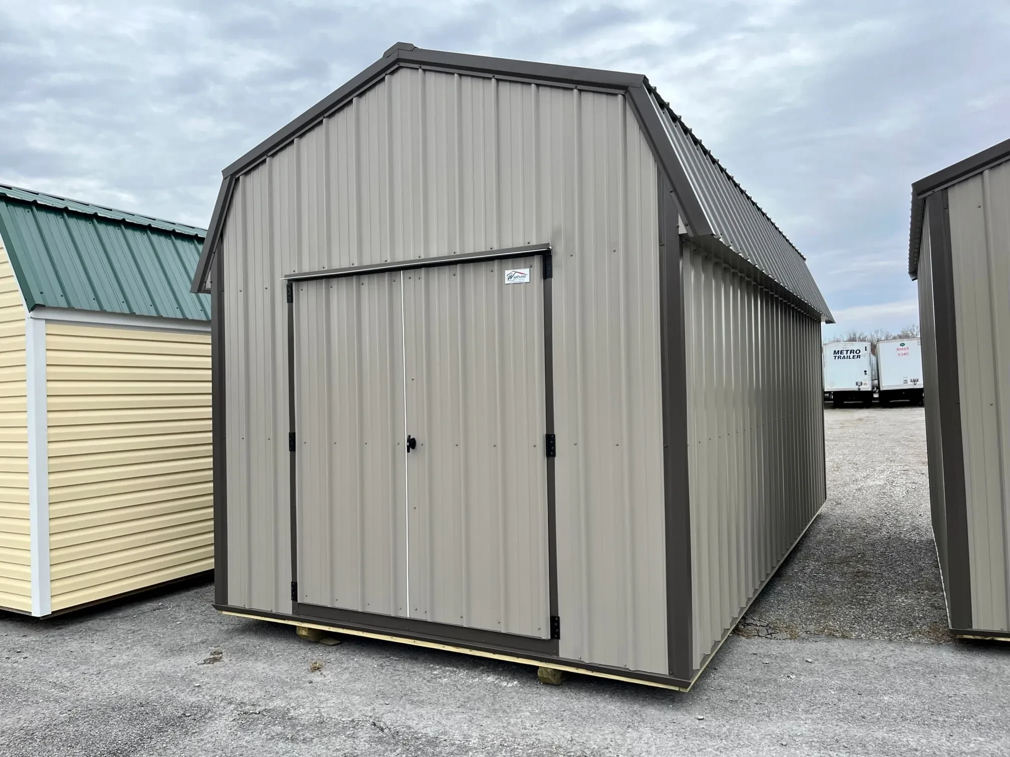 a clay colored metal lofted barn with bronze colored trim and roof