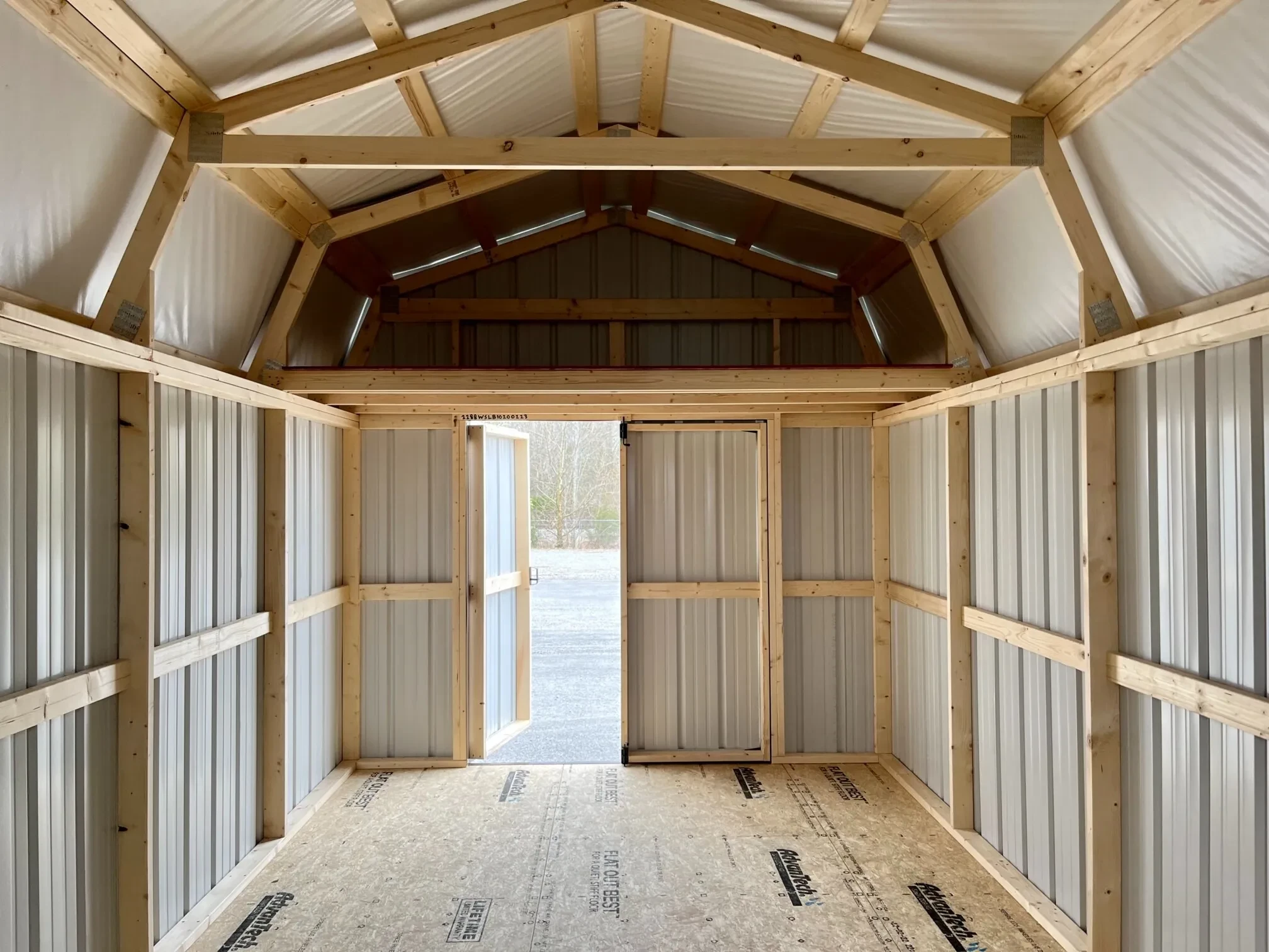 inside a metal lofted barn looking at the double doors, which one door is open and there is a 4' loft above the doors