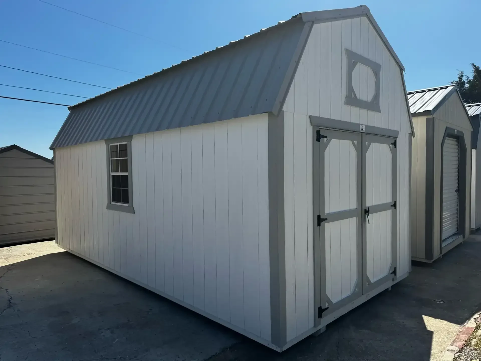 a white lofted barn with double doors in the front and a 24"x36" window on the left side