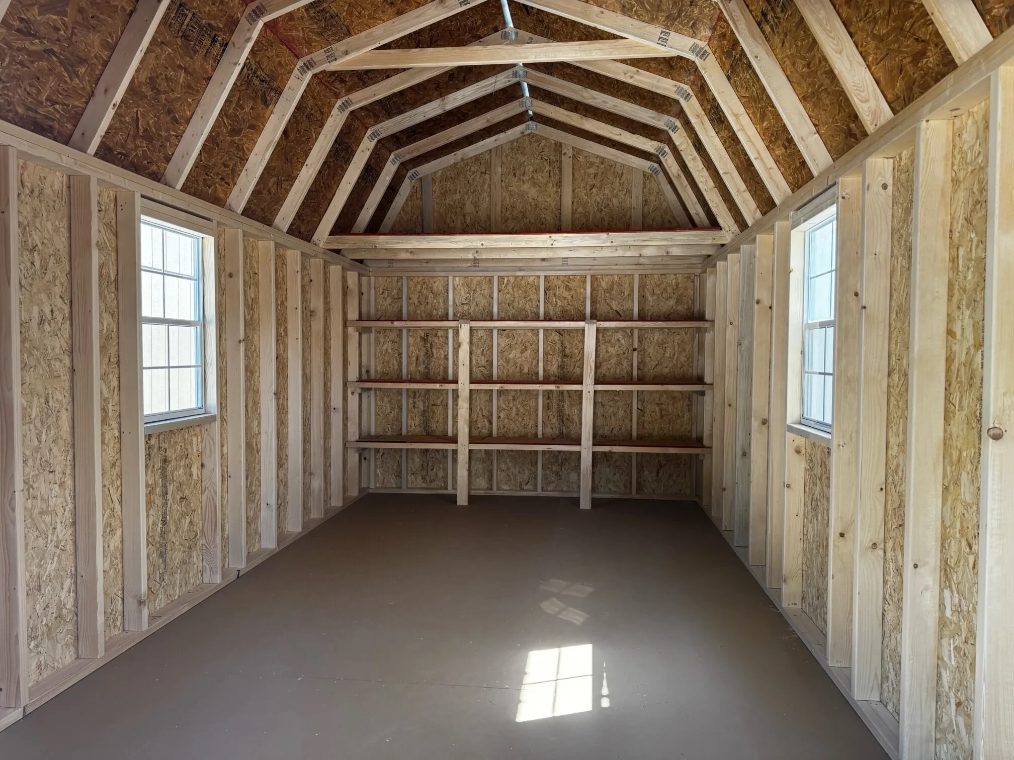 inside a wood lofted barn with a 2x3 window on each side wall and triple shelves under a 4' loft on the back wall