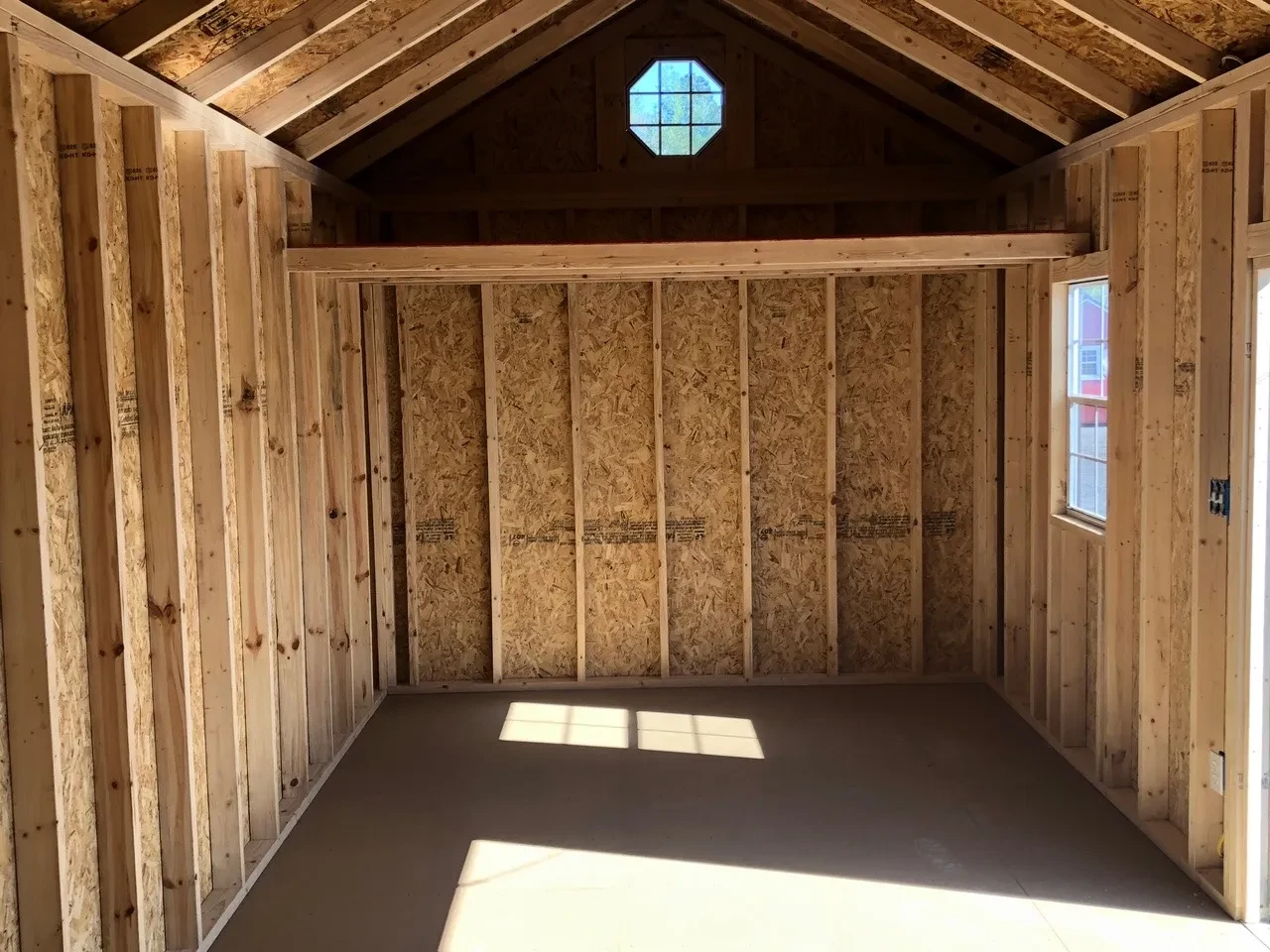 inside a wood garden shed with a loft and an octagon window above it
