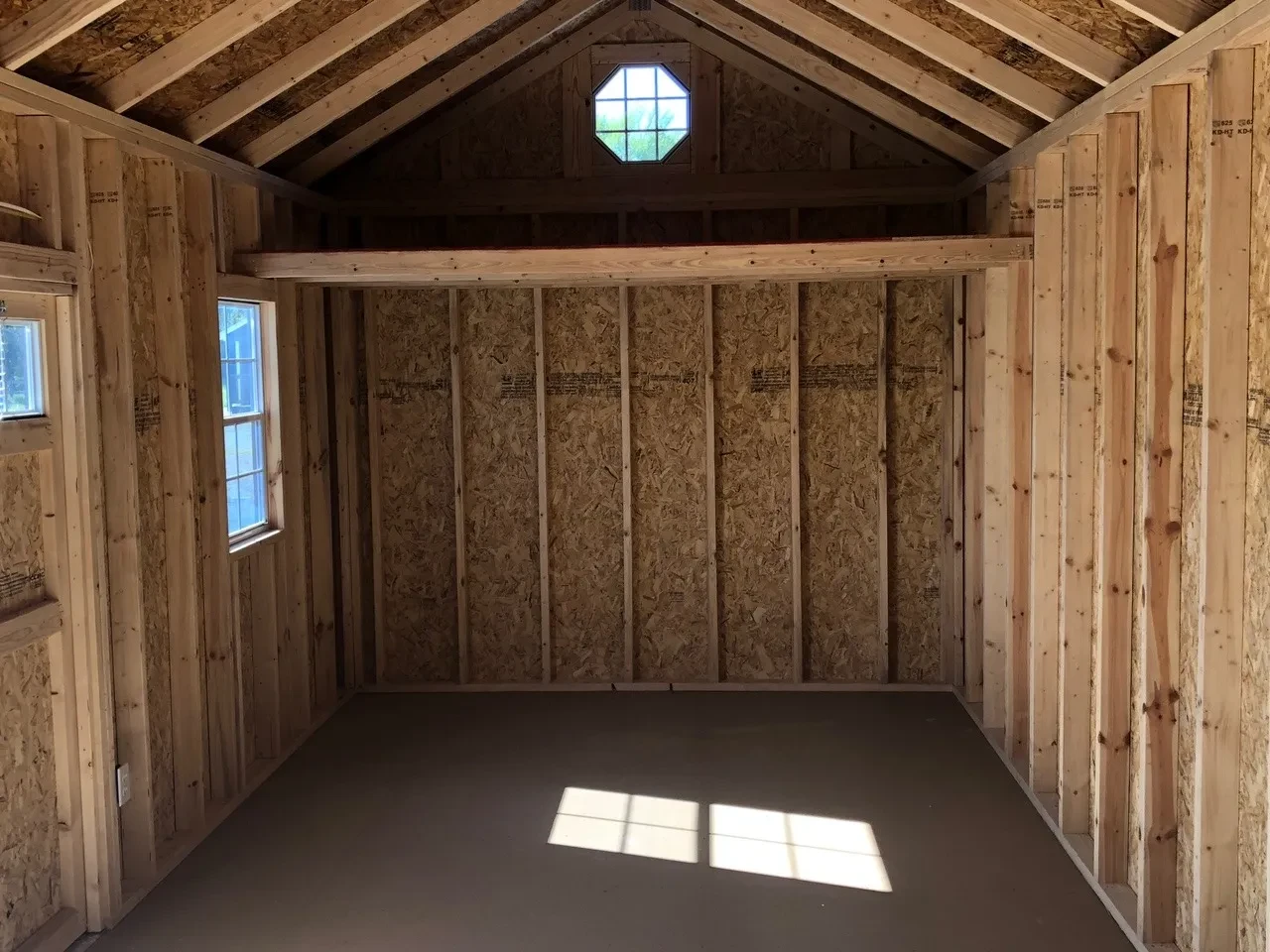 the interior of a wood garden shed with a loft, an octagon window, and a 2x3 window