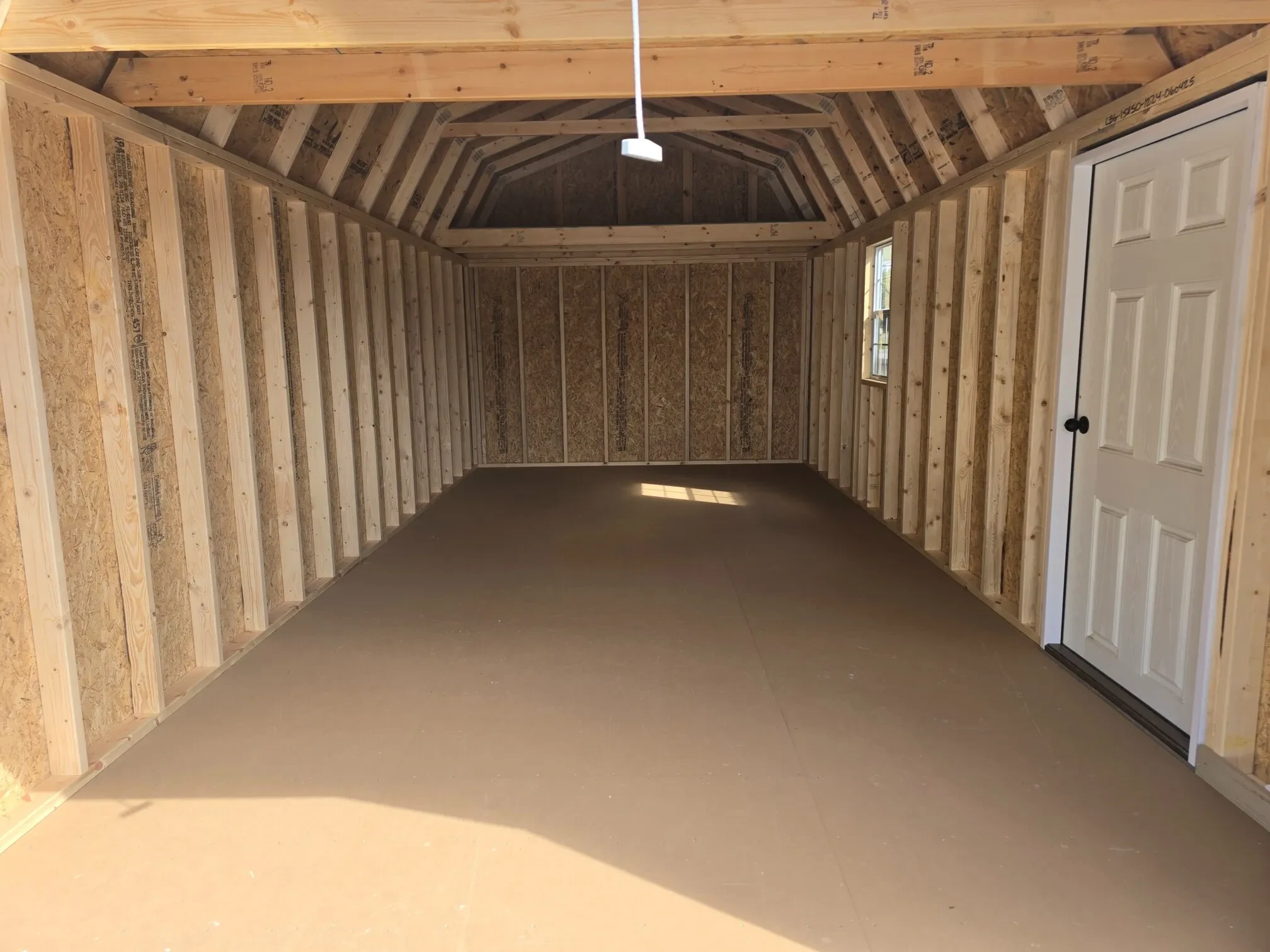 the interior of a lofted garage with a loft, a window, and a walk-in door