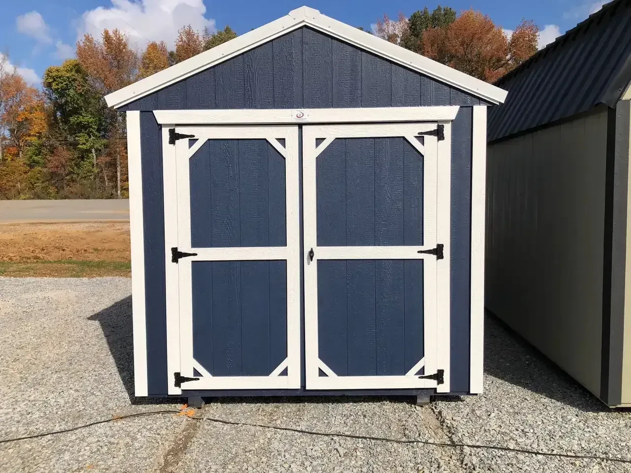 a small blue wood shed with double doors and white trim