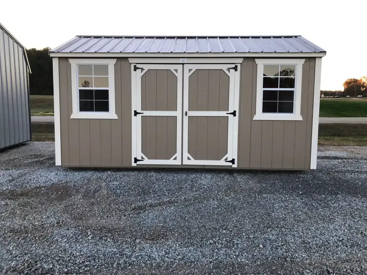 a garden shed with double doors and two windows