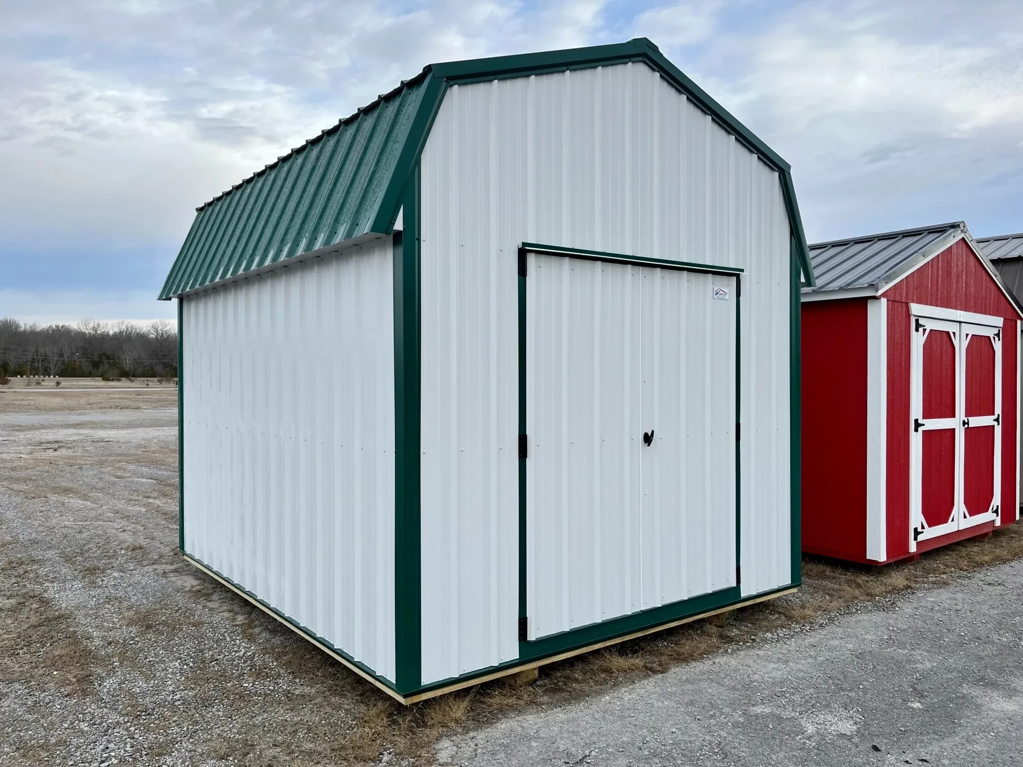 a white metal lofted barn with a forest green roof and white double doors