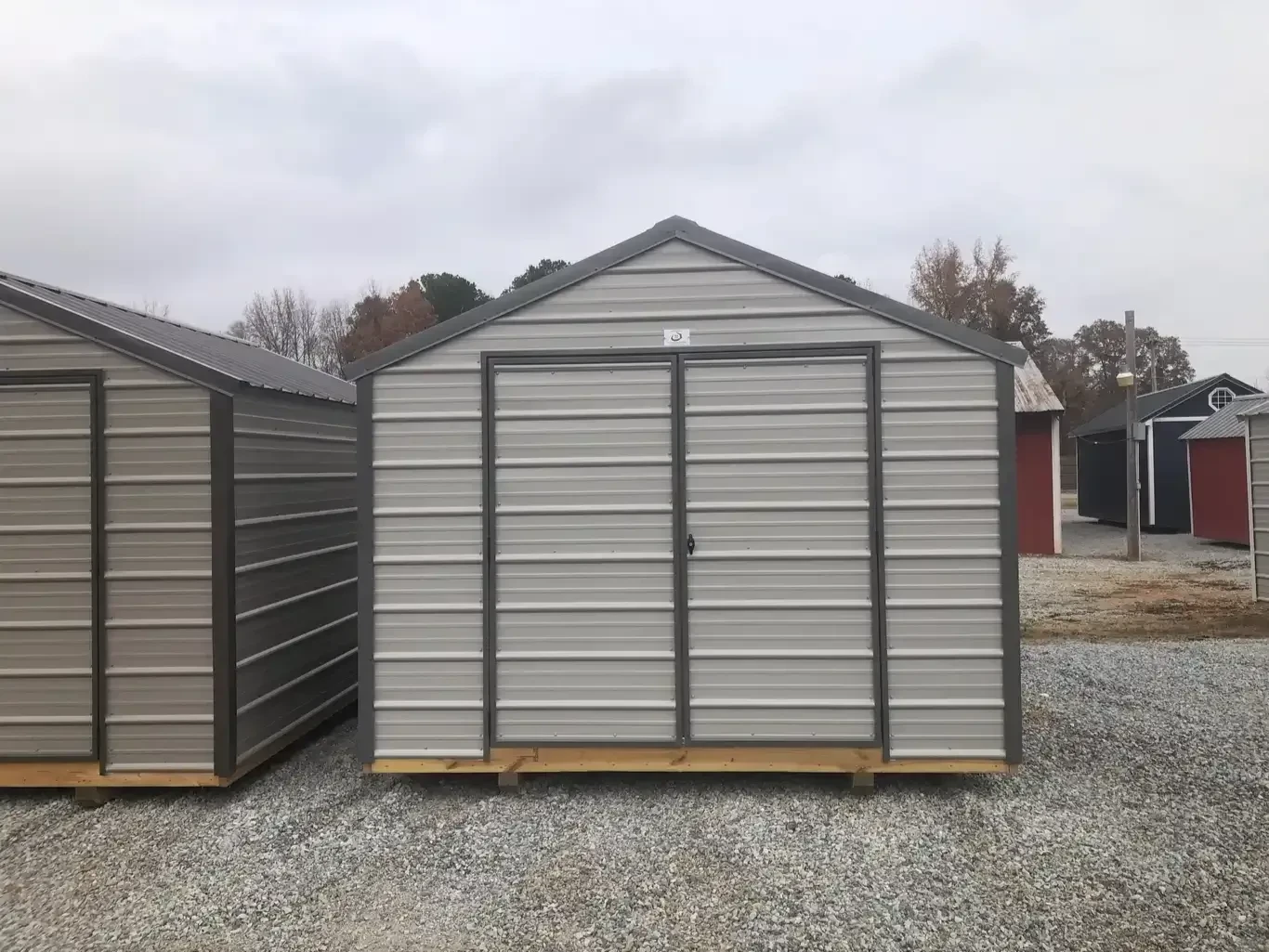 a gray metal shed with double doors and charcoal colored roof and trim