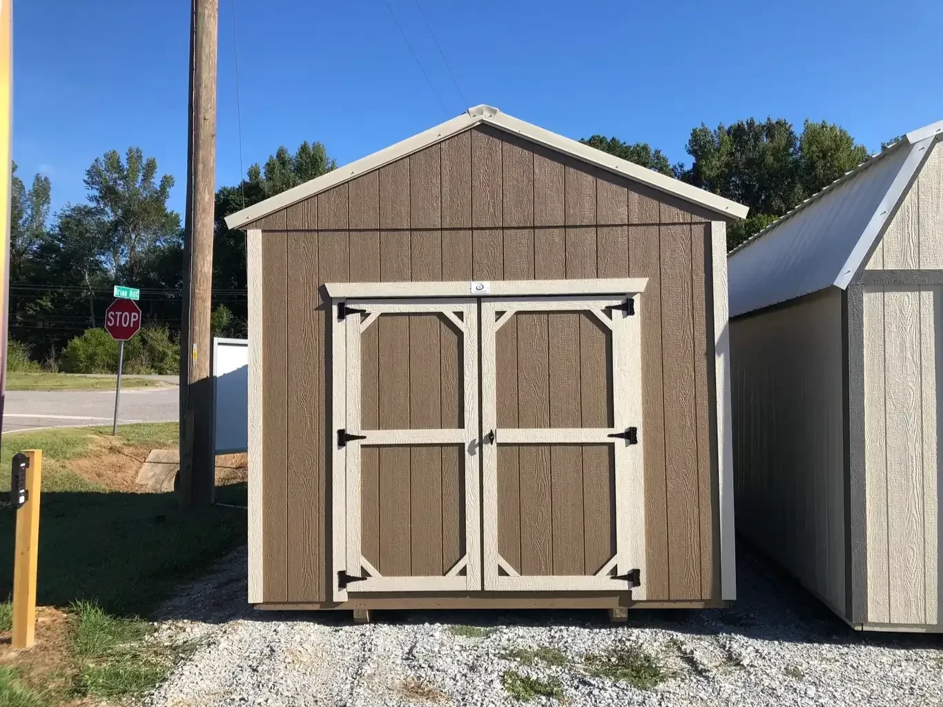 a pine bark colored wood utility shed with 72" double doors and light stone colored trim and roof
