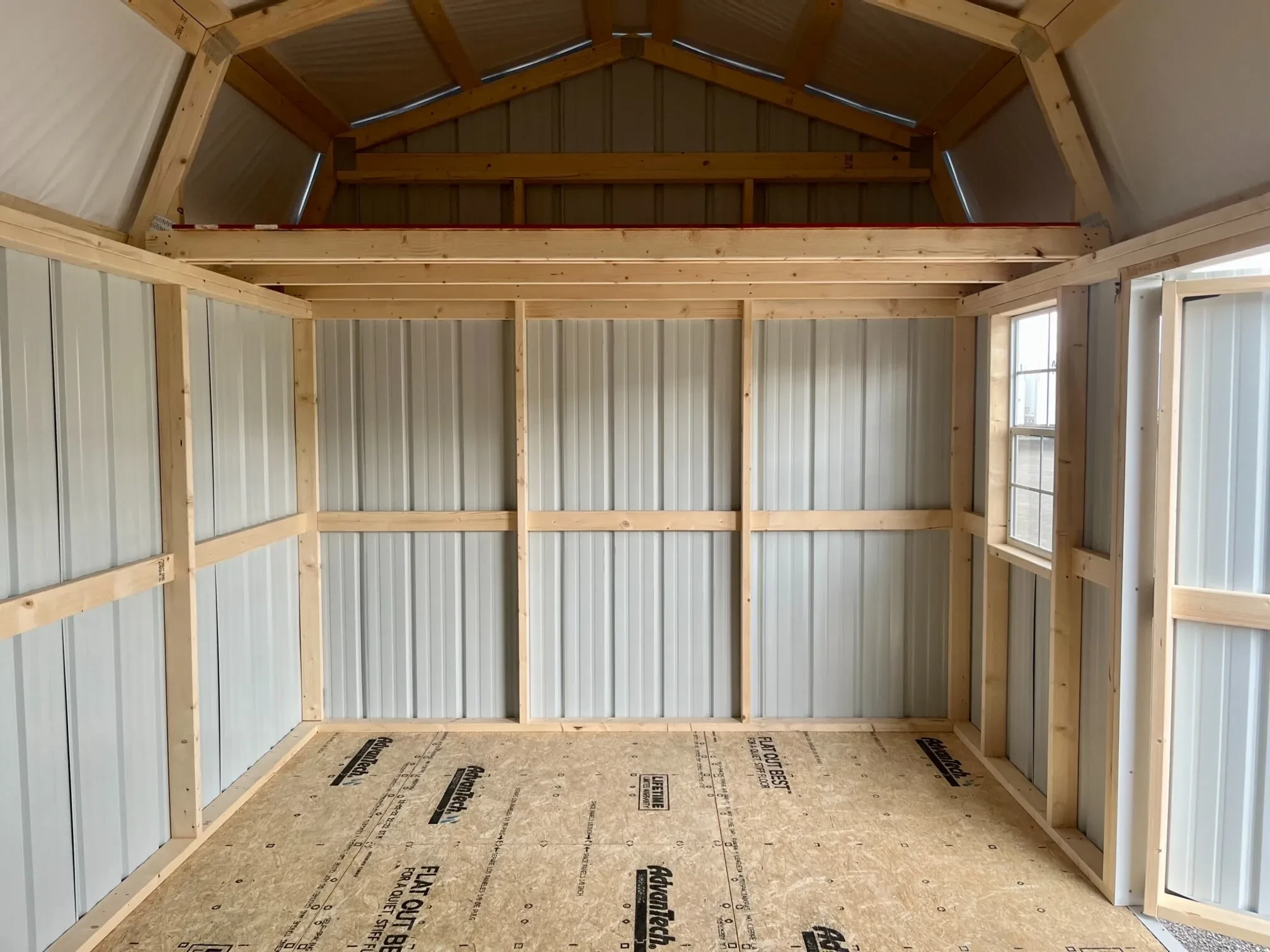 the right interior side of a side lofted barn that has a loft and a window