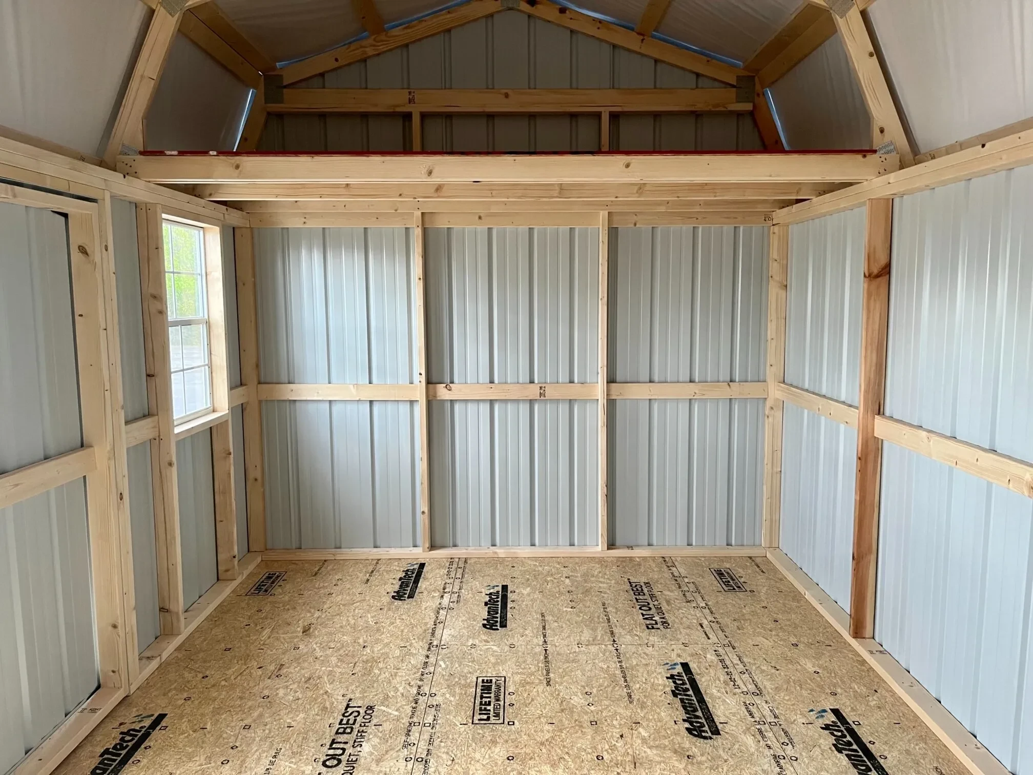 the left interior side of a metal side lofted barn with a loft and a window