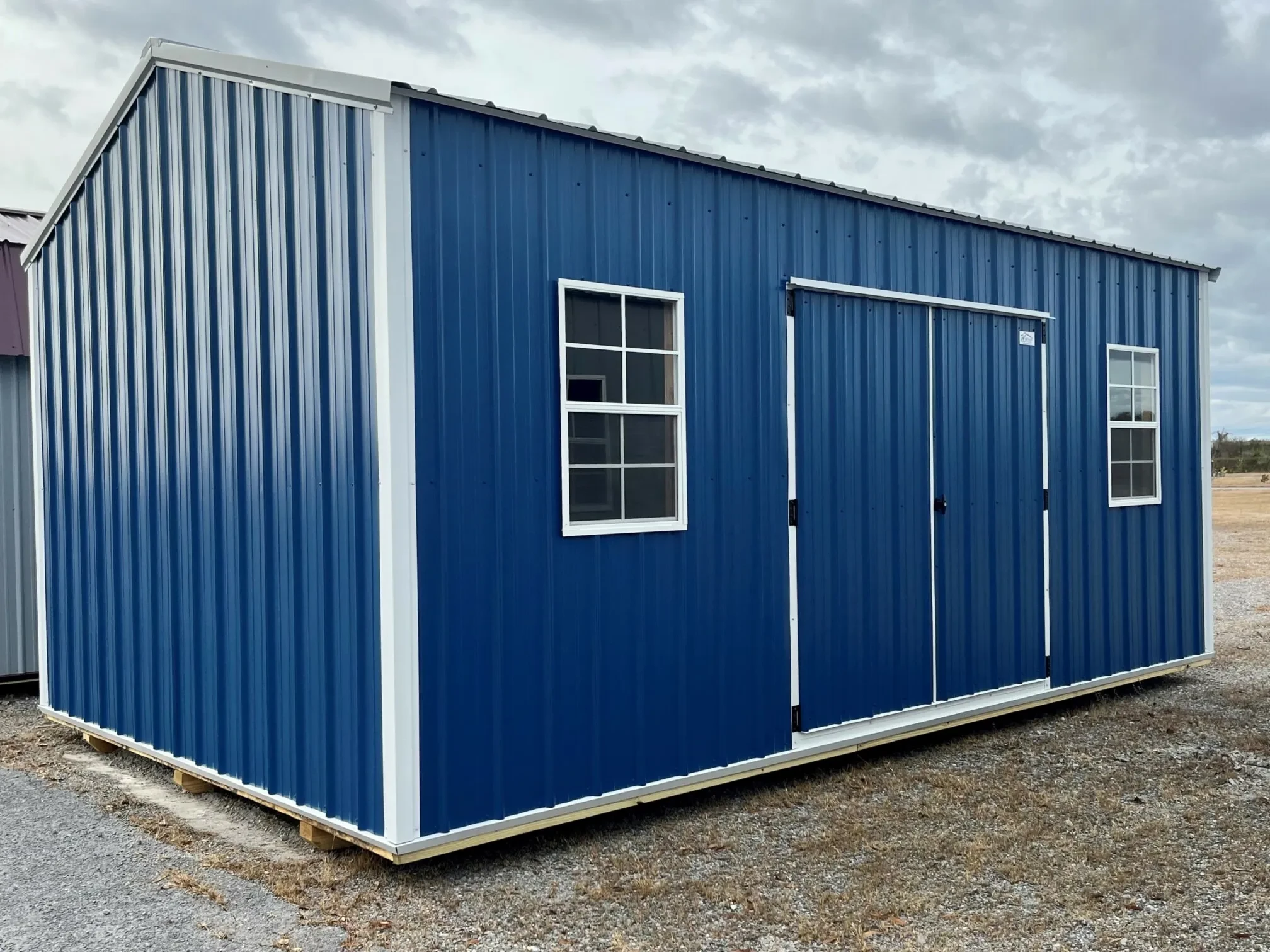 a bright blue classic metal shed with double doors in the side and two windows