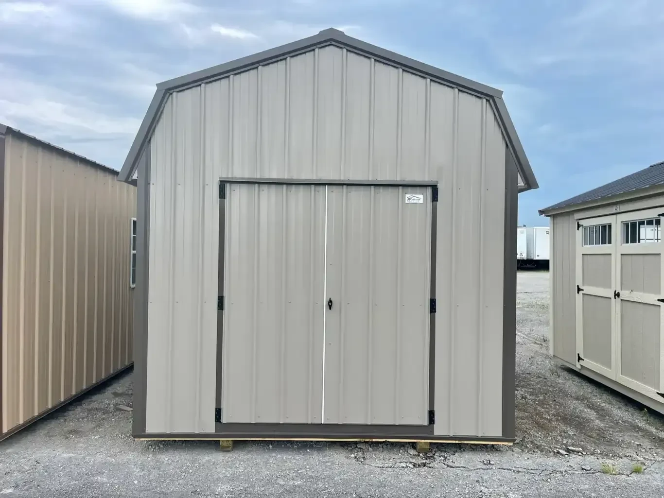 a clay colored metal lofted barn with double doors and bronze colored trim and roof