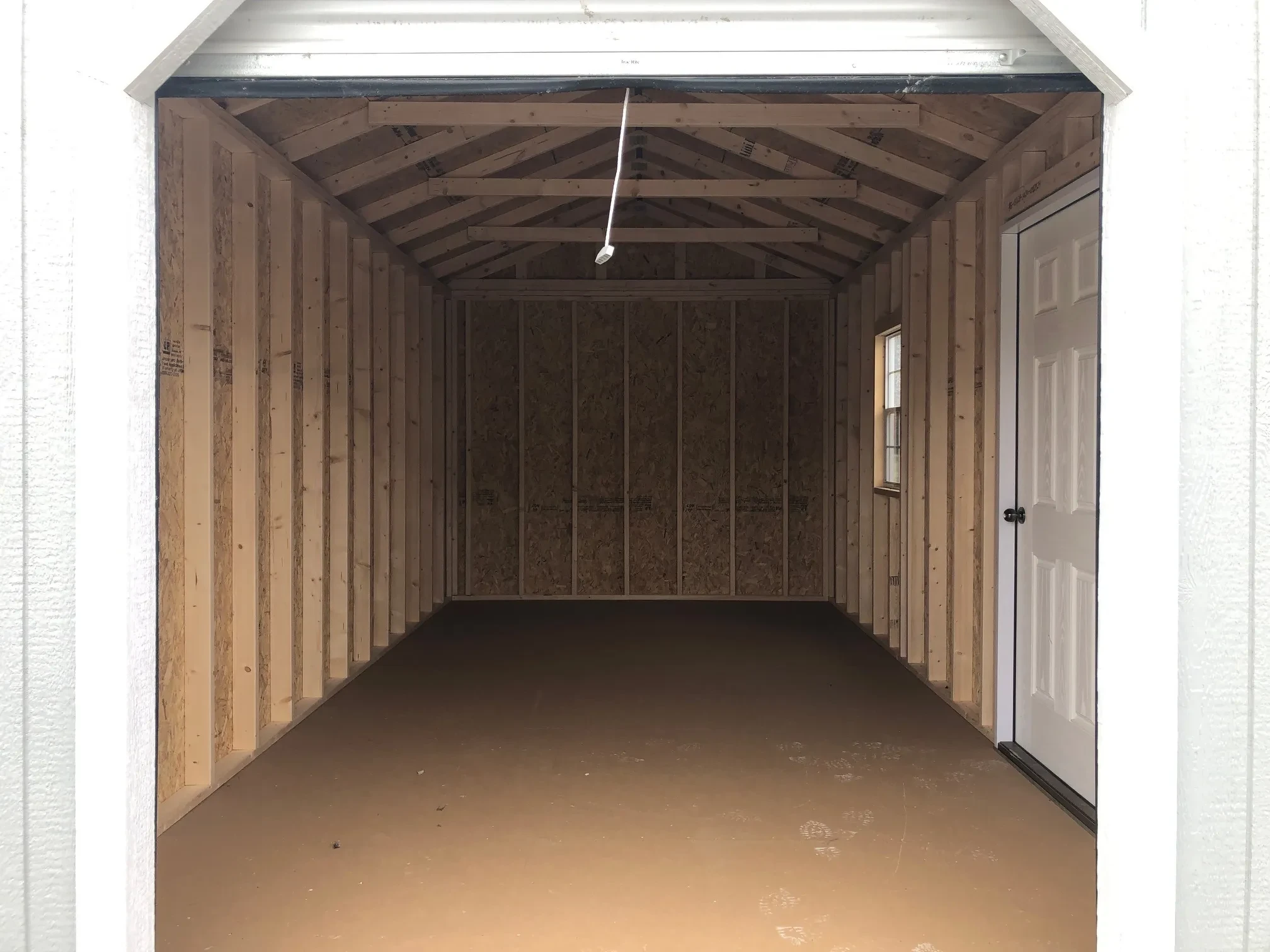 looking through a 6x7 rollup door that is open into a garage with a window and walk-in door