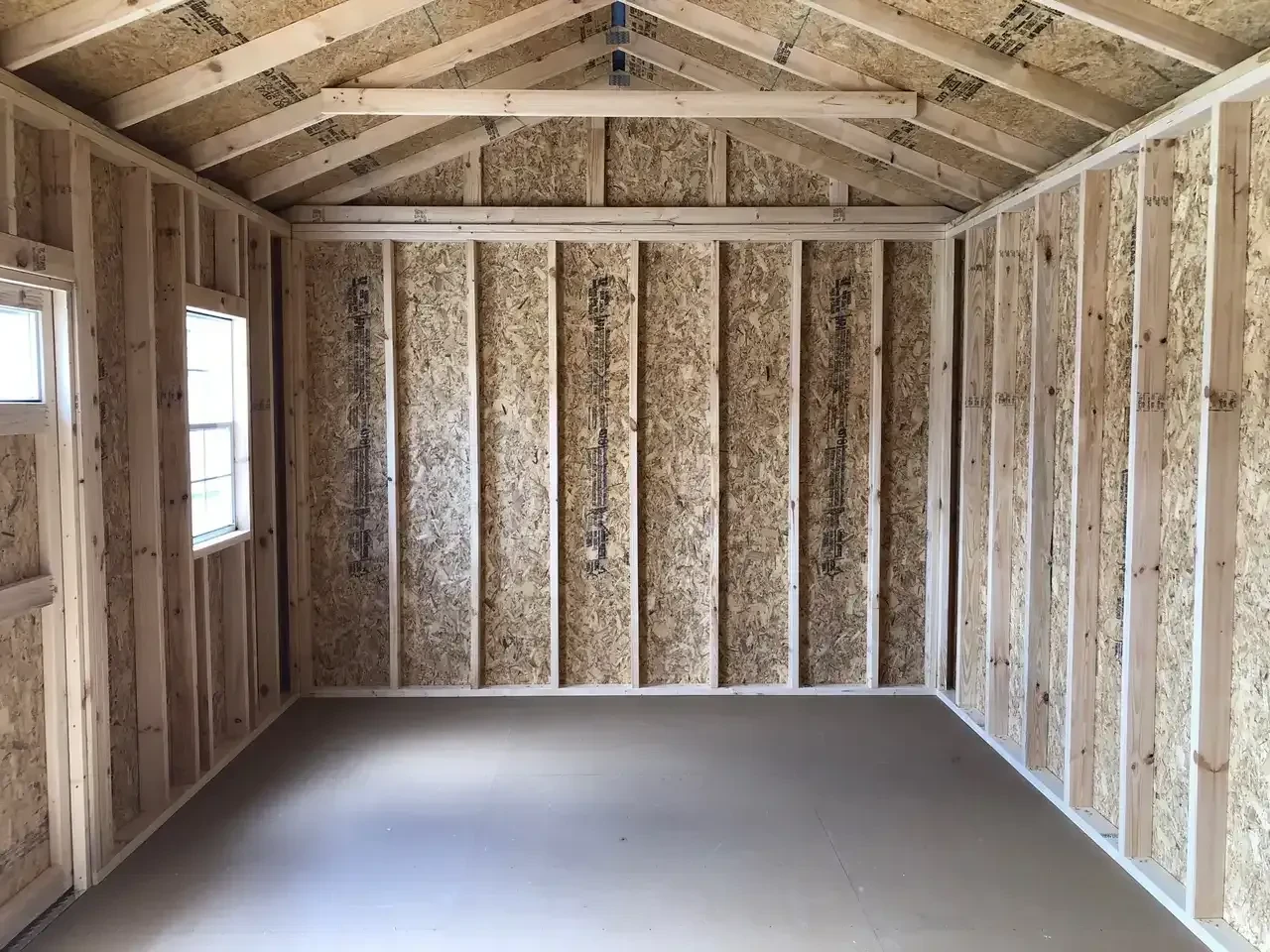 the left interior side of a wood garden shed showing a window on the front wall