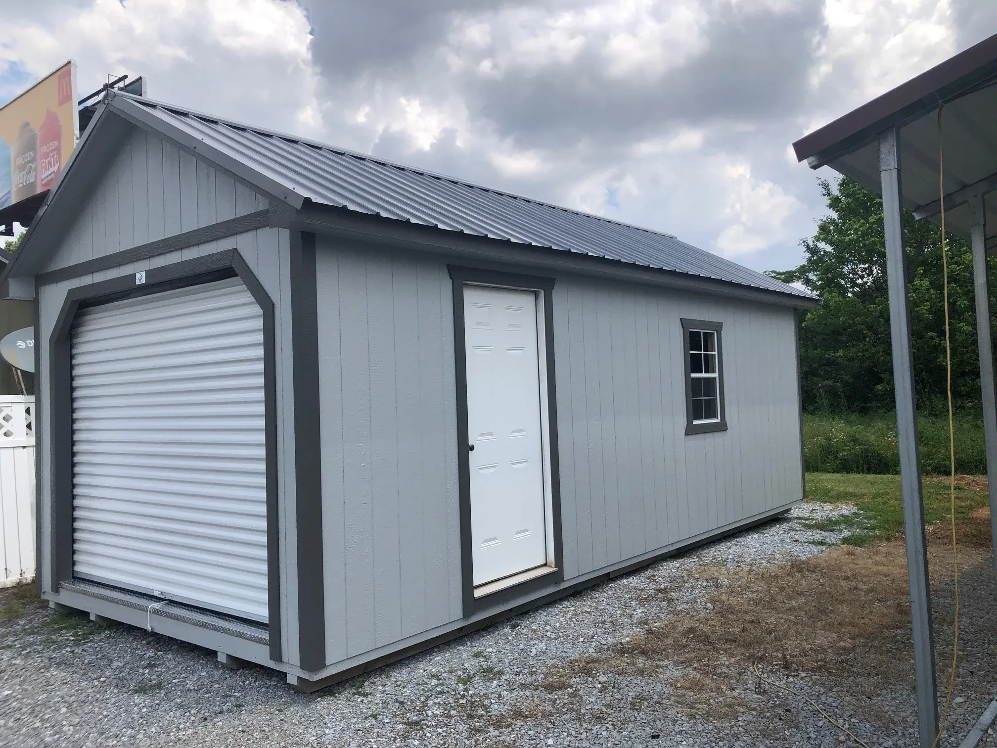 a wood garage shed with a 9x7 rollup door in the front, and a walk-in door and 2x3 on the right wall