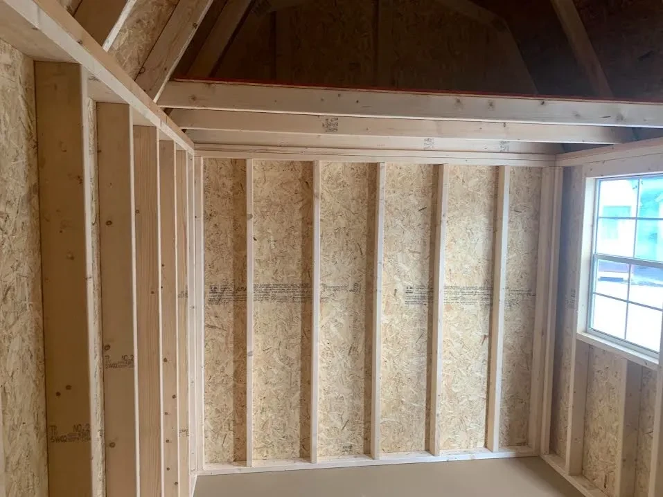 inside a wood side lofted barn with a loft on the left and a window in the front wall