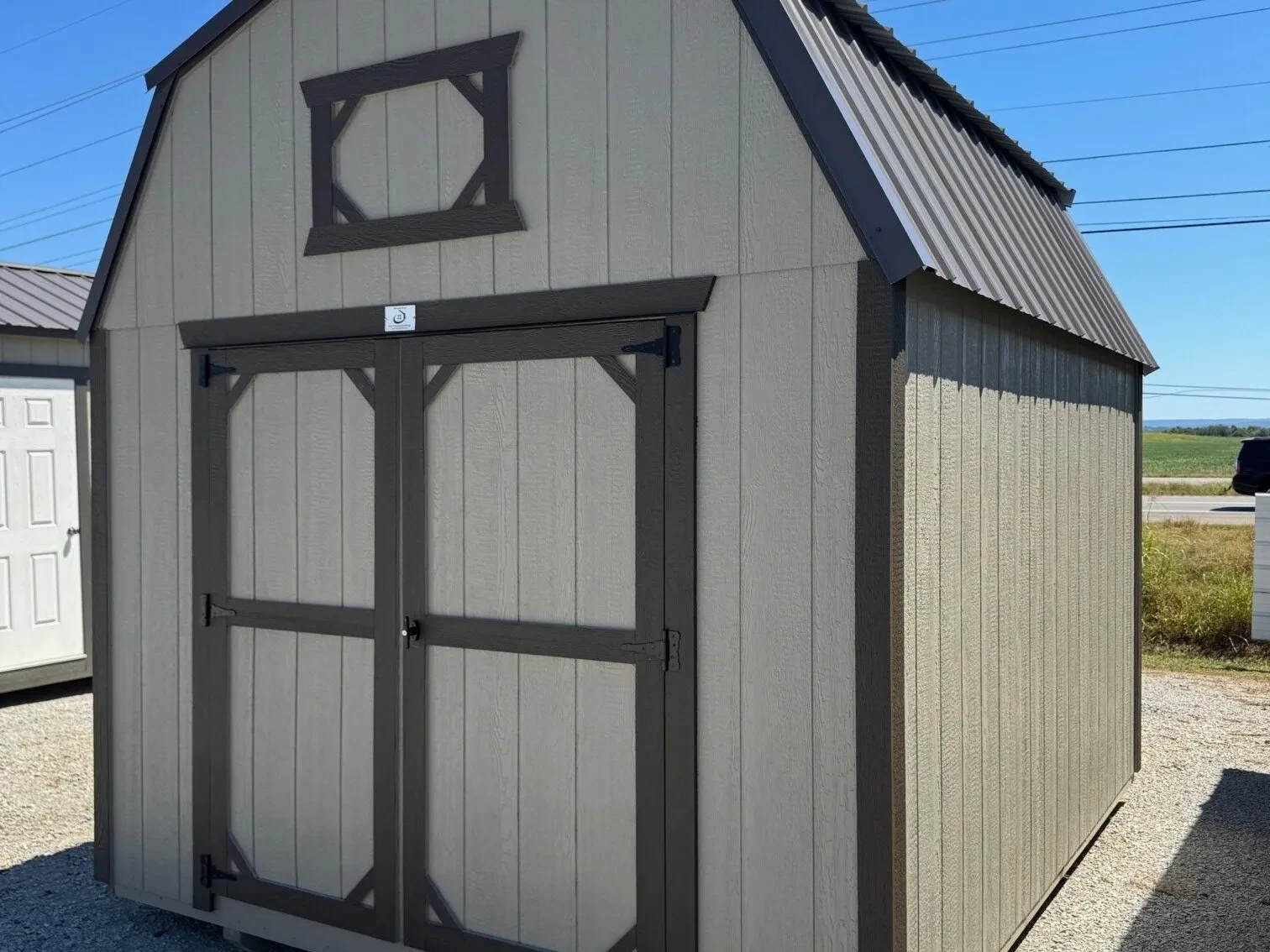 a clay colored wood lofted barn with double doors and decorative loft trim
