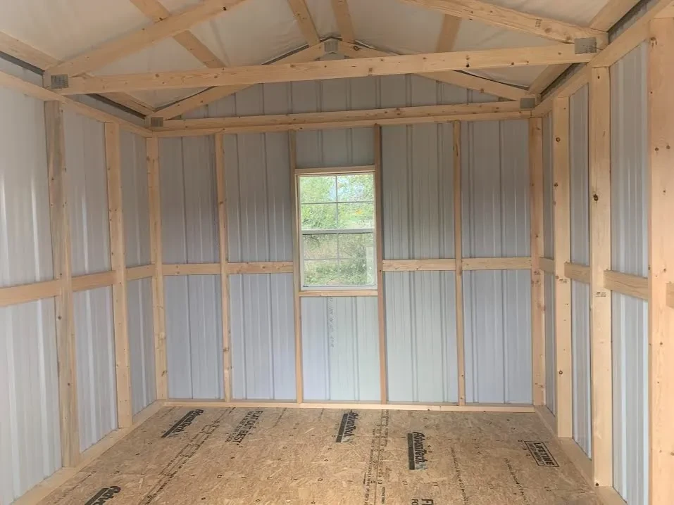inside a metal utility shed looking at the back wall which has a window in the middle of it