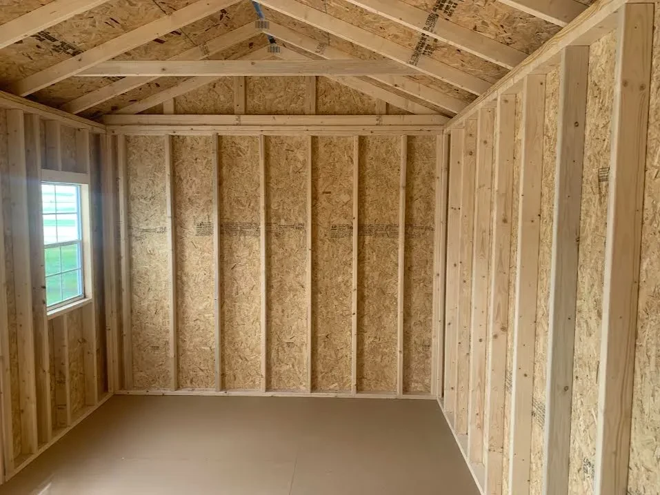 the inside of a wood garden shed with a solid floor and lumber framing visible