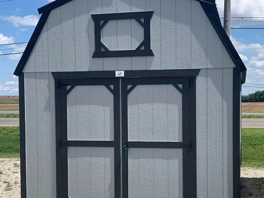 a gray lofted barn with black trim. It has double doors and decorative loft trim above them