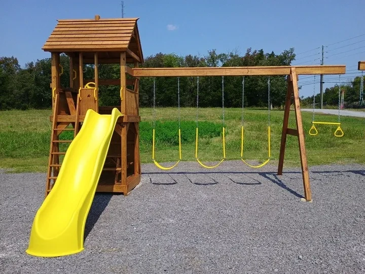 A wood sandbox tower playset with yellow trapeze bar, swings, and slide