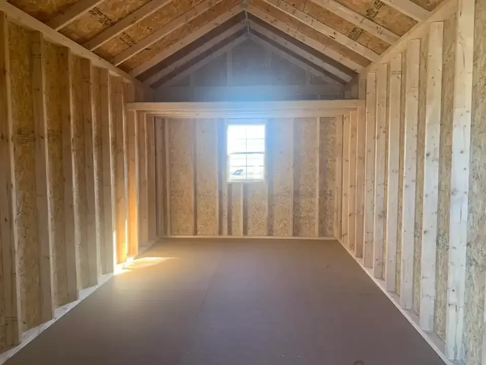 inside a wood utility shed. It has a window in the middle of the back wall and a loft above it.