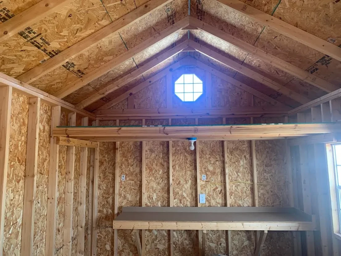 inside a wood garden shed look at the right wall which has an octagon window above a 4' loft, above a workbench