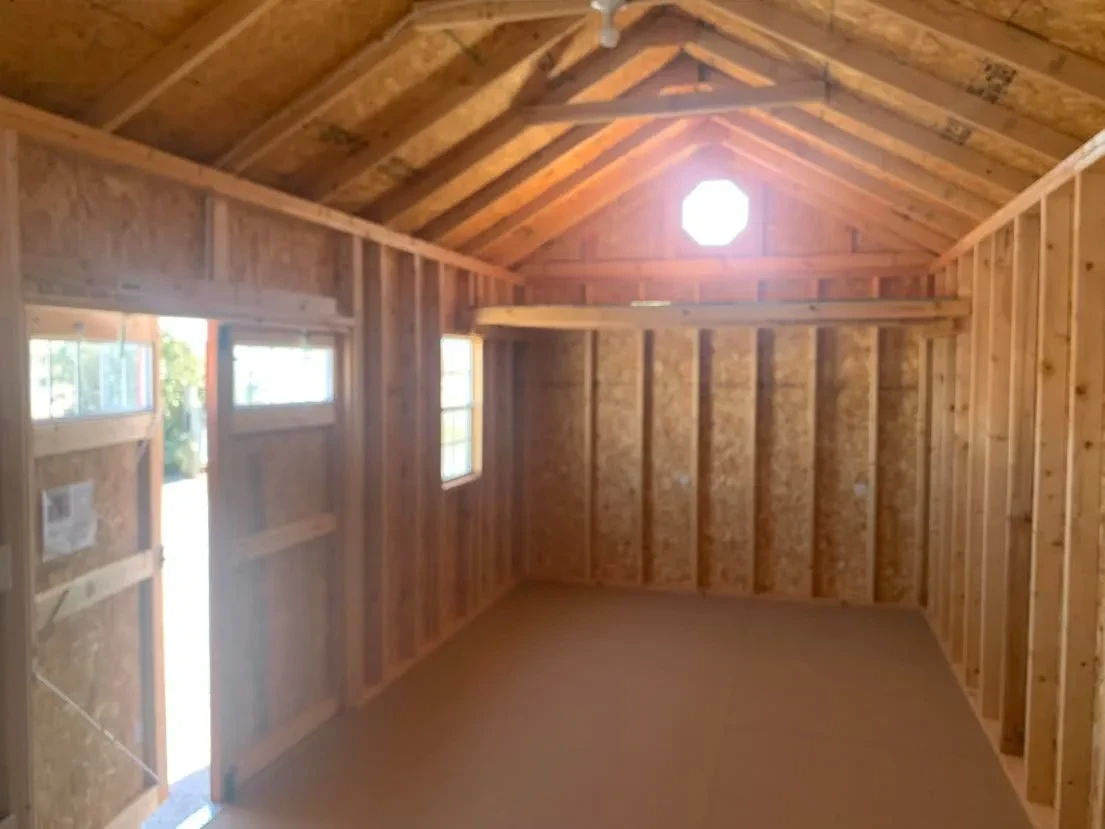 inside a garden shed looking at the left wall, it has an octagon window above a 4' loft