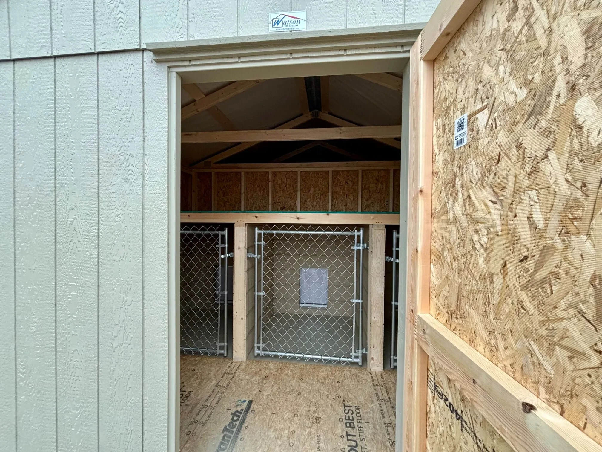 looking inside the single barn door into the dog kennel. It has three small chain link gates for dogs to go through