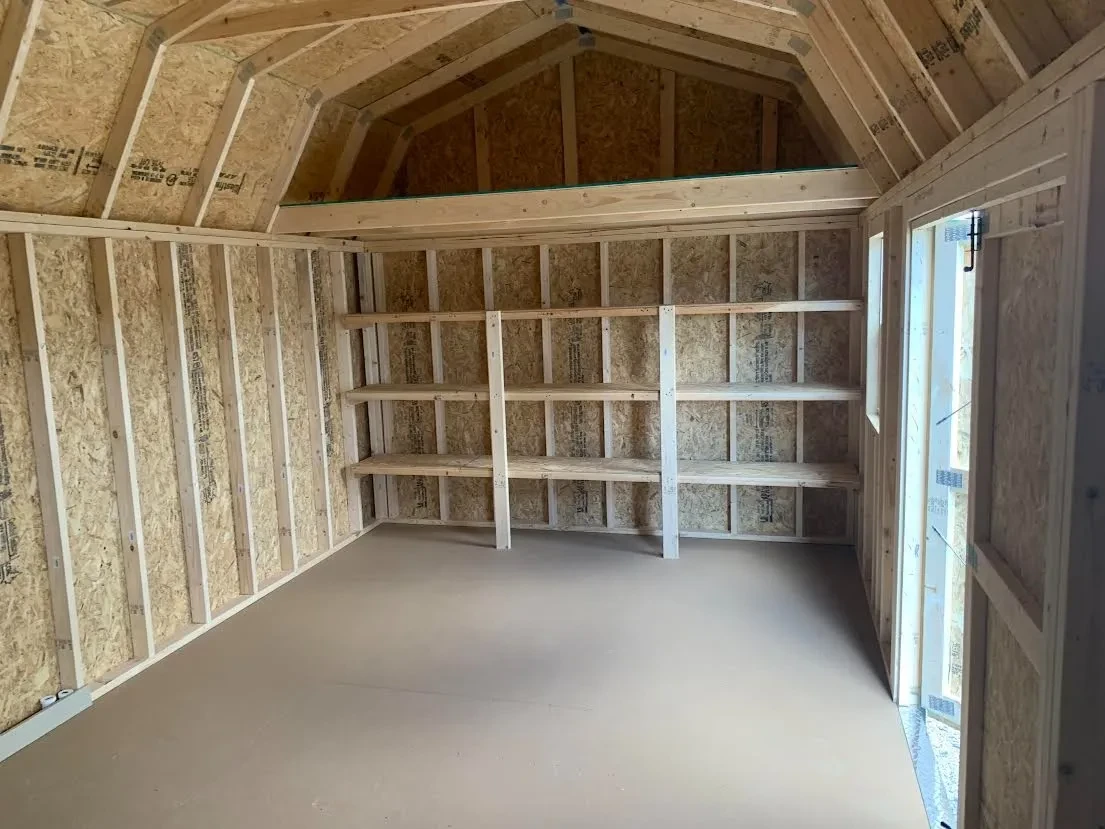 inside a lofted barn looking at the left wall. It has 3-tier shelving and a loft against the wall