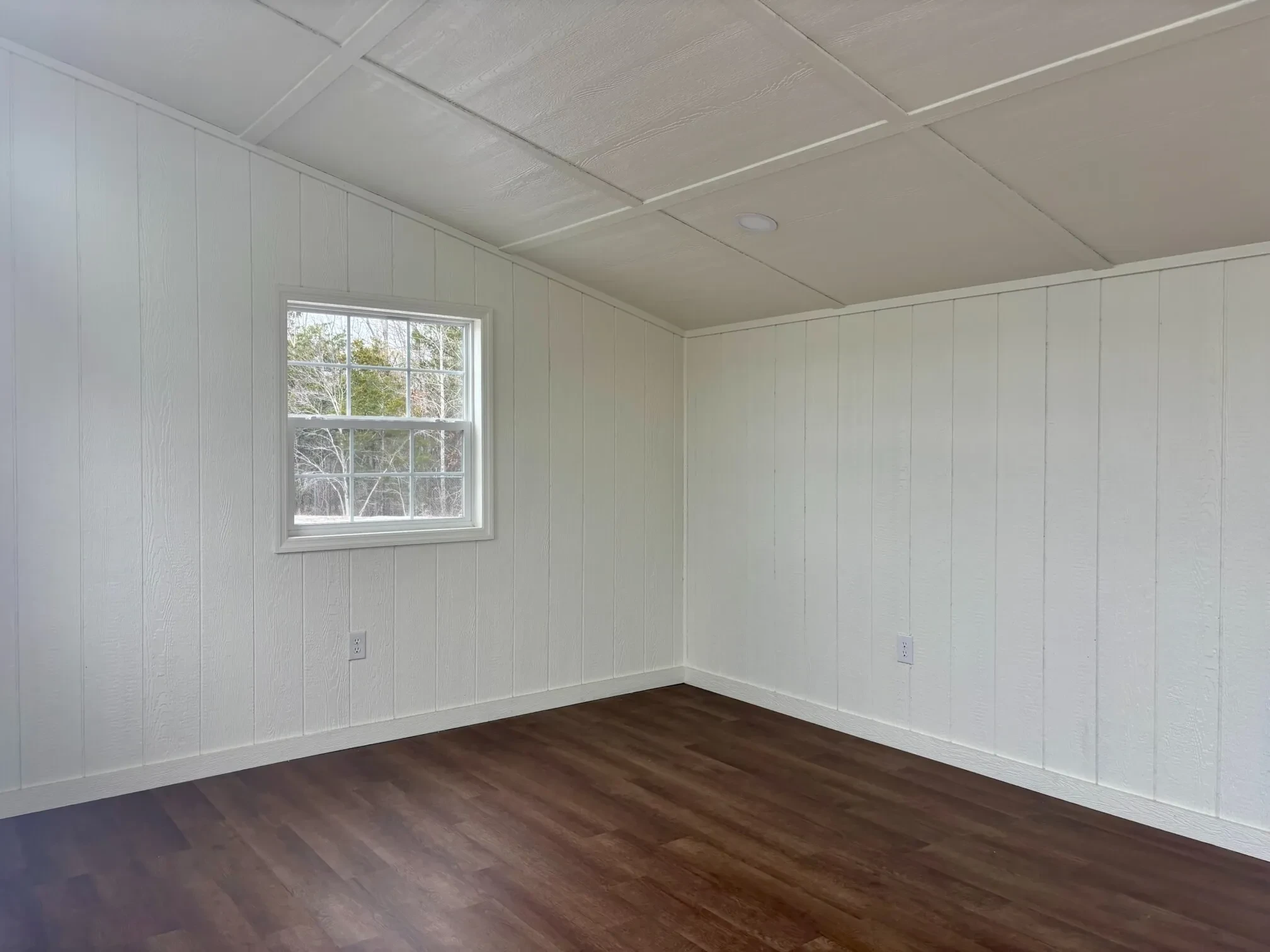 the back left corner of a finished out studio shed. There is a window on the side wall