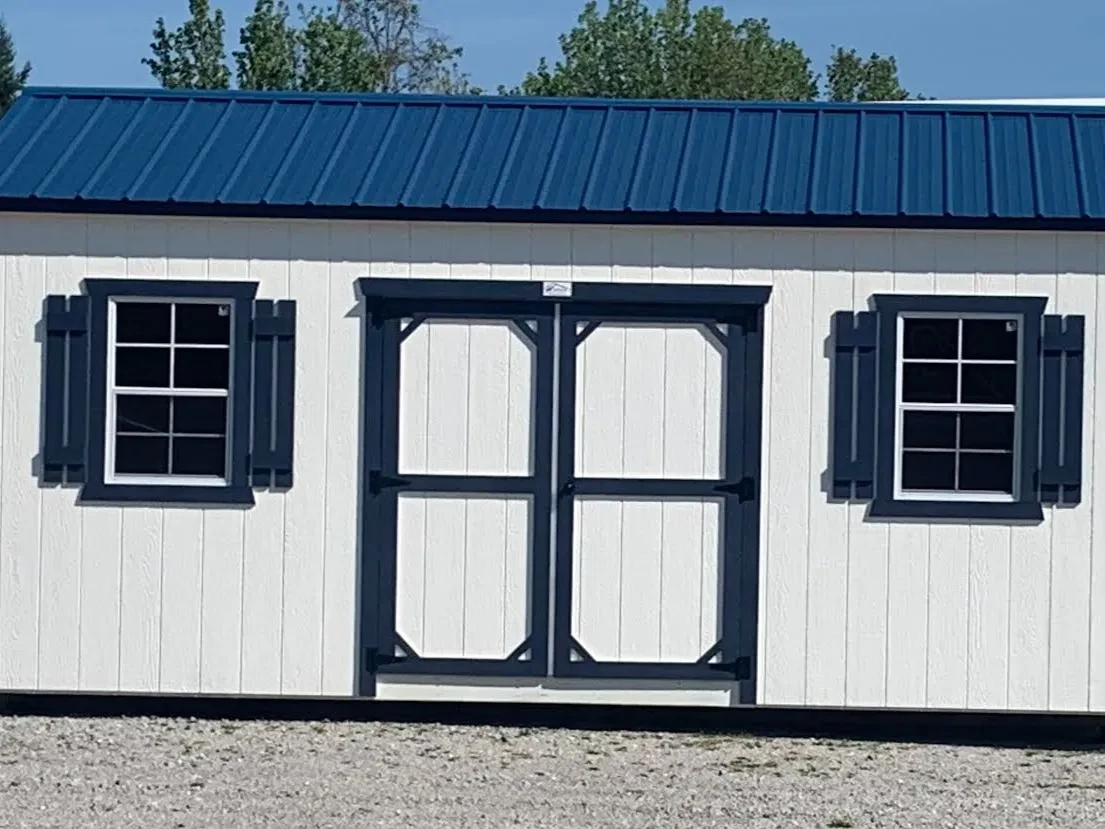 white garden shed with blue trim. It has double doors and a window on each side of the doors