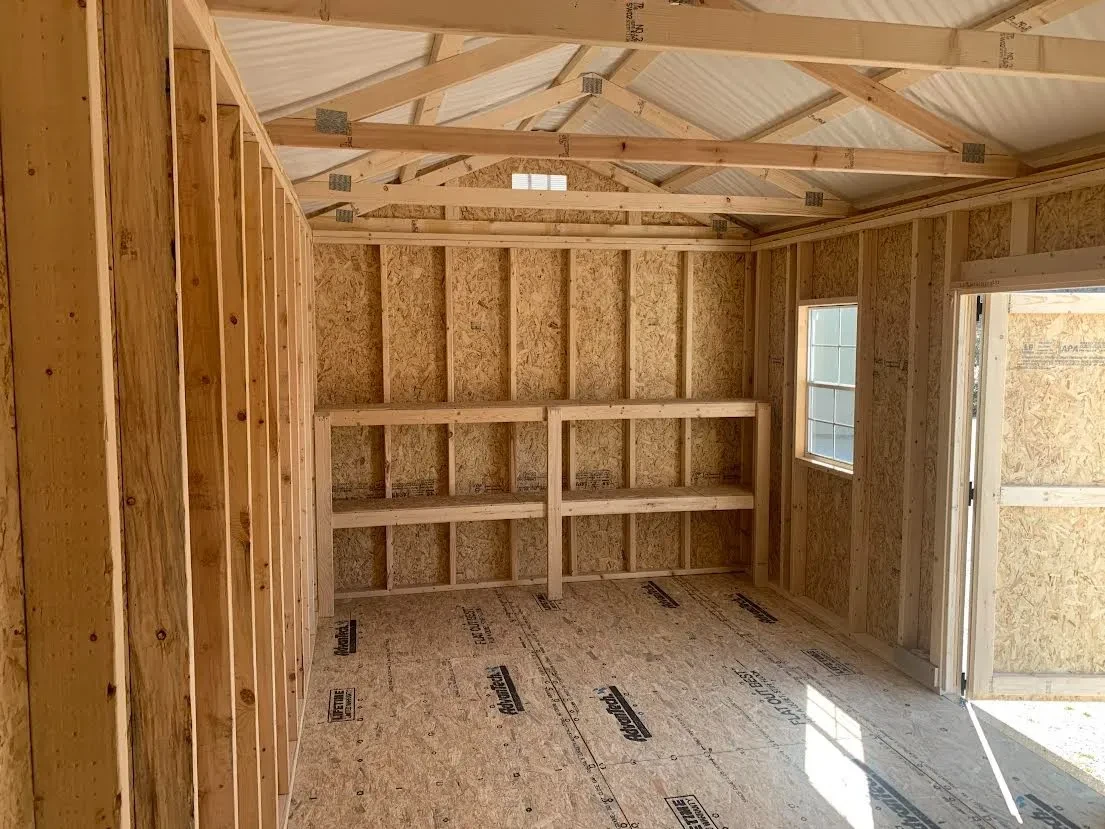 inside a wood garden shed looking at the left wall. It has double shelves and a vent towards the top of the wall