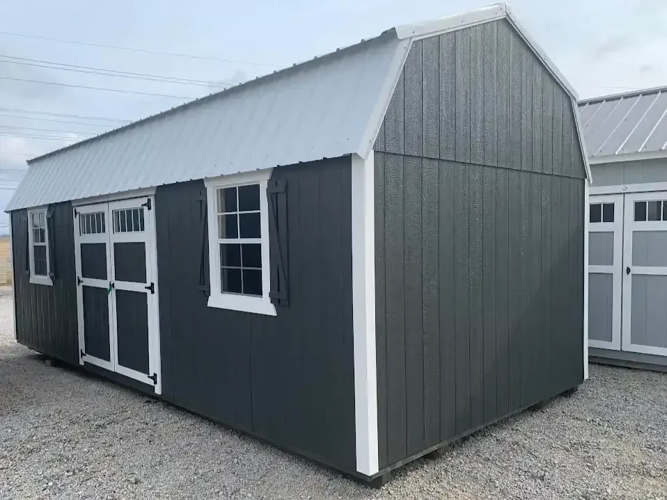 large burnished slate colored side lofted barn with two windows with shutters and double doors