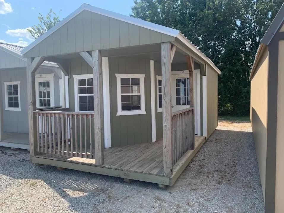 a beige cabin with a wrap around wood porch and multiple windows. It has a 9-Lite walk-in door as well