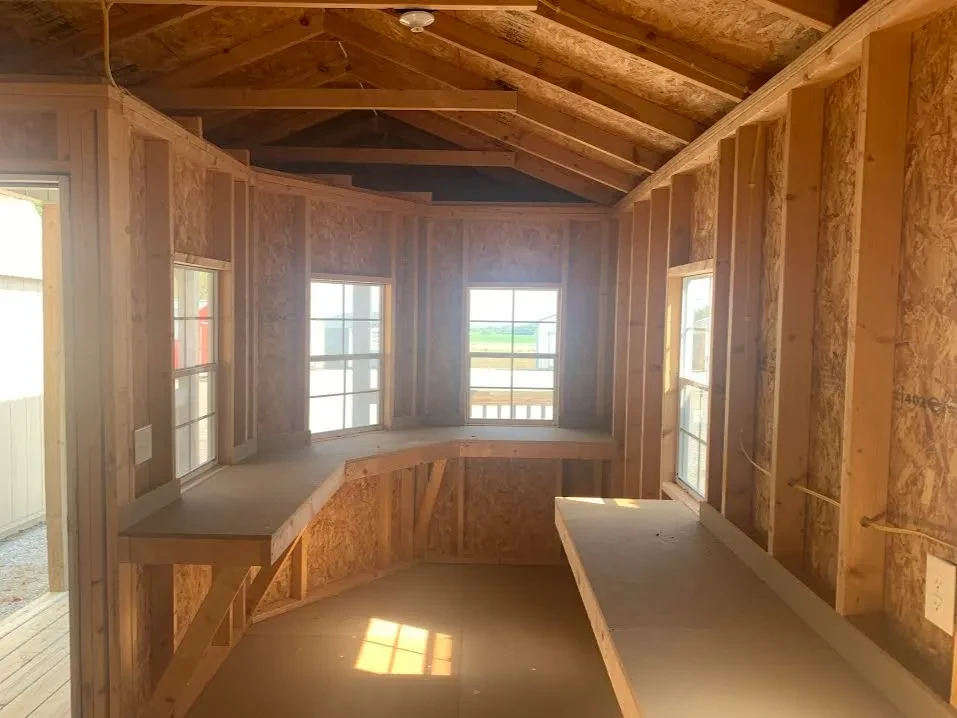 inside a wood cabin looking at the windows that have workbenches under them