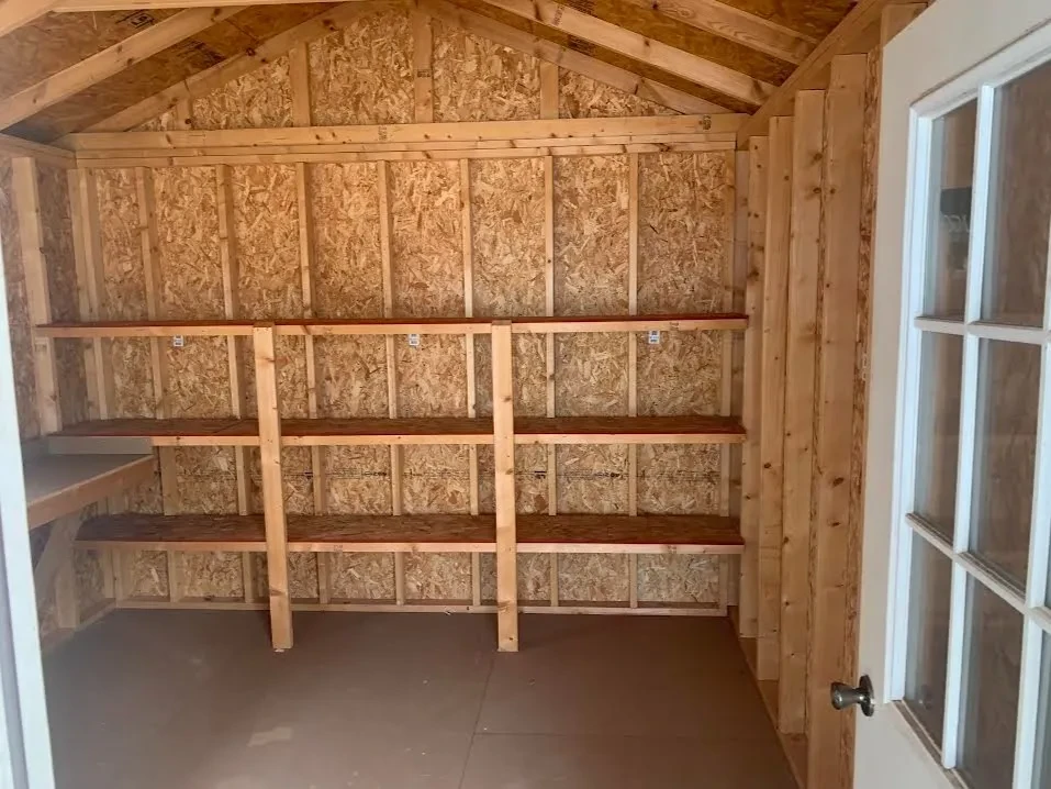 inside a wood cabin looking at the back wall which has 3-tier shelving
