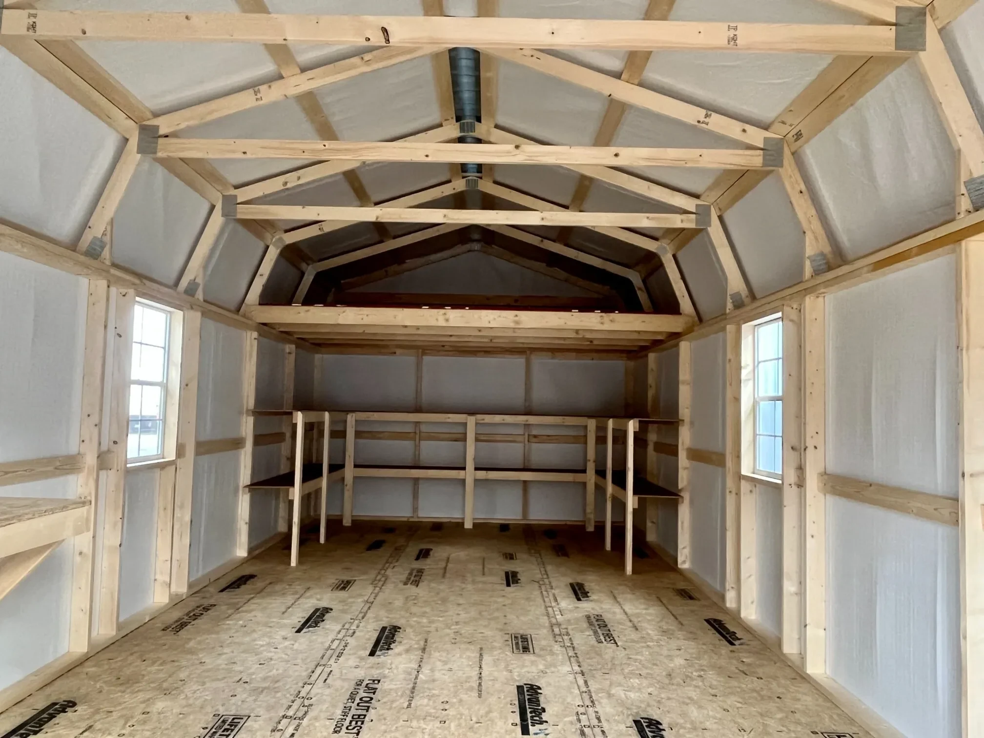 inside a large lofted barn looking at the back wall. It has double shelving and a large loft along the back wall