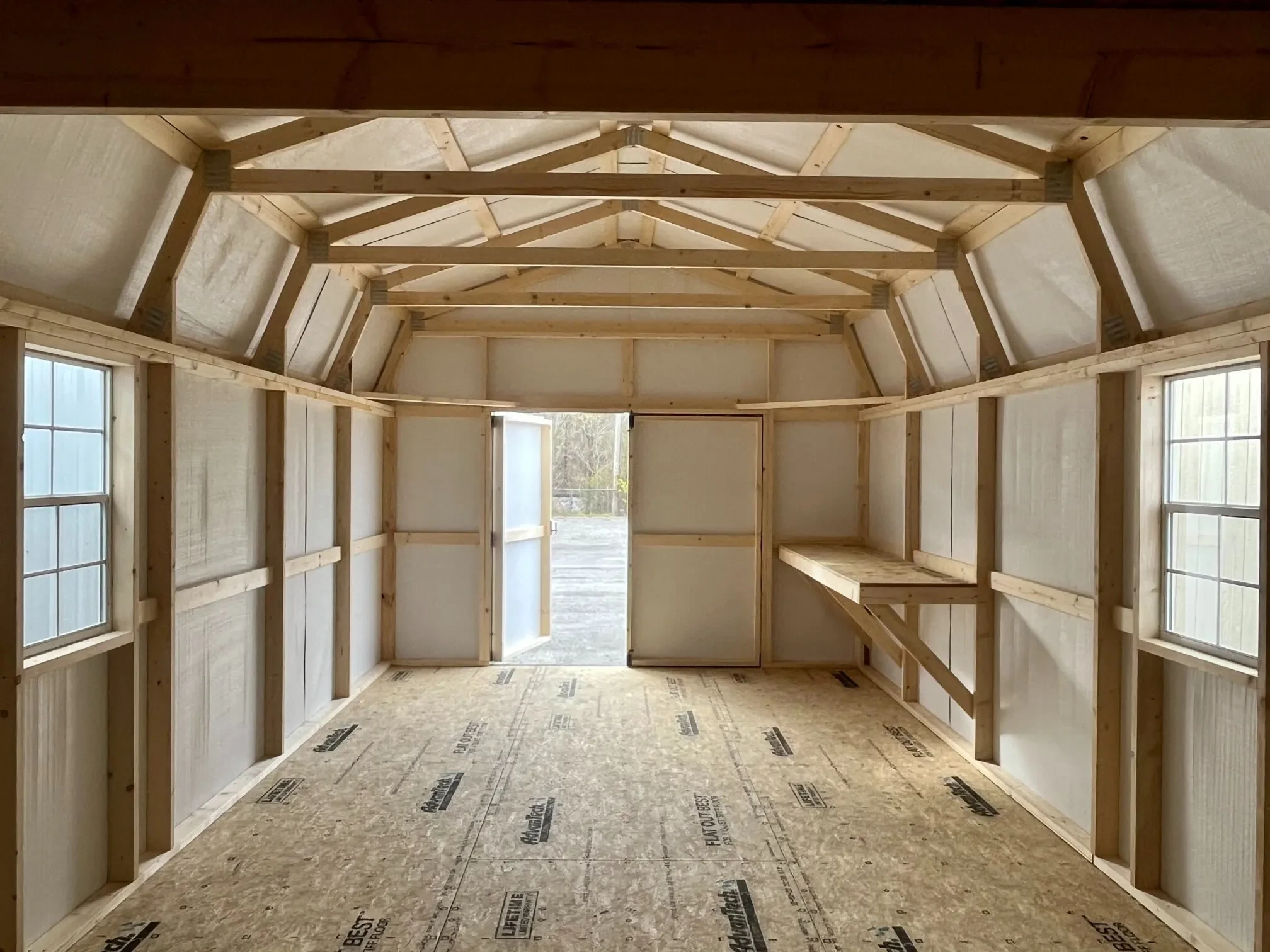 inside a metal lofted barn looking at the front wall which has open double doors and a workbench and window on the right wall
