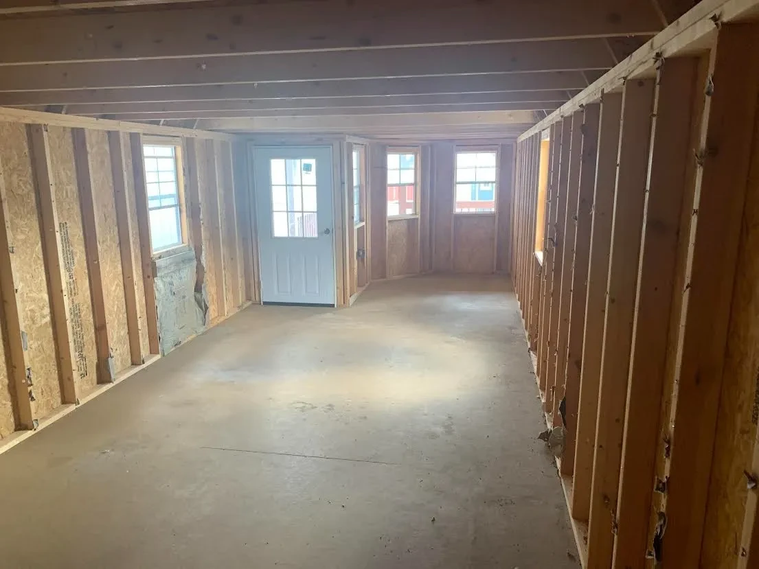 inside a large lofted cabin looking towards the front which shows a walk-in door and four windows