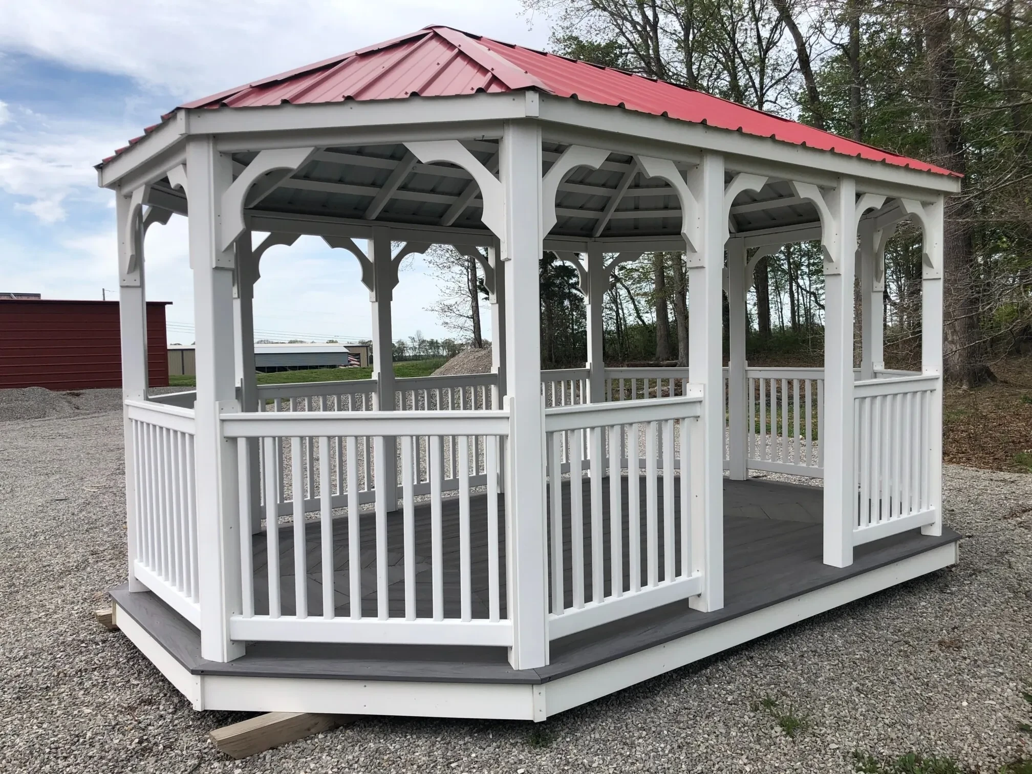 a large white vinyl gazebo with posts and railings. It also has a red metal roof