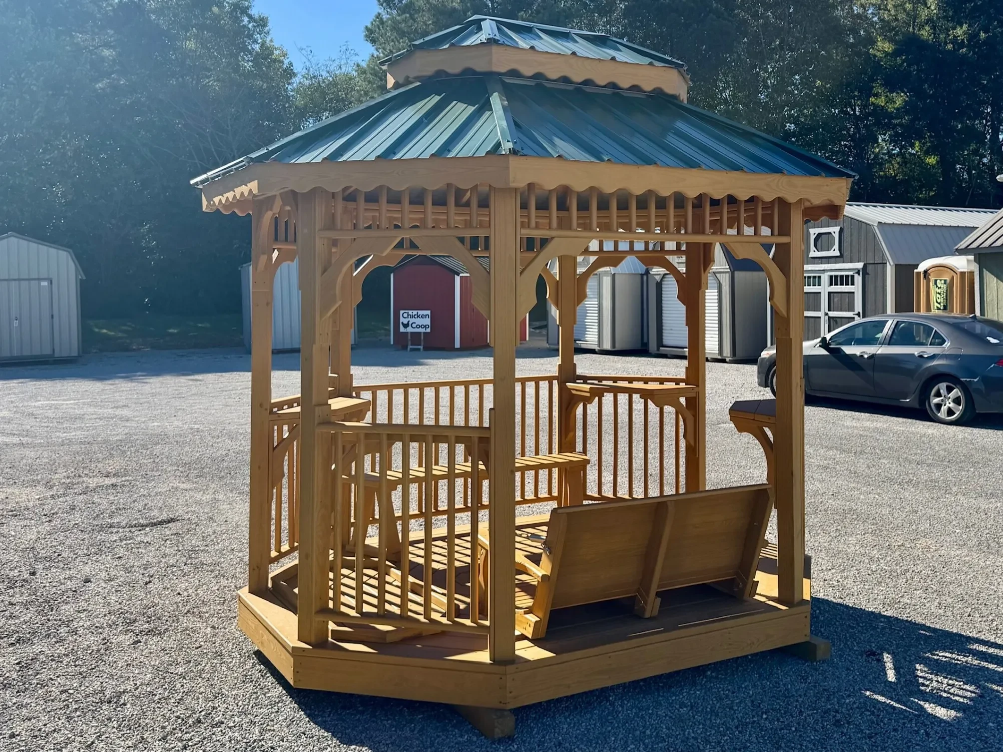 a wood stained brown teahouse with a green metal roof and benches inside