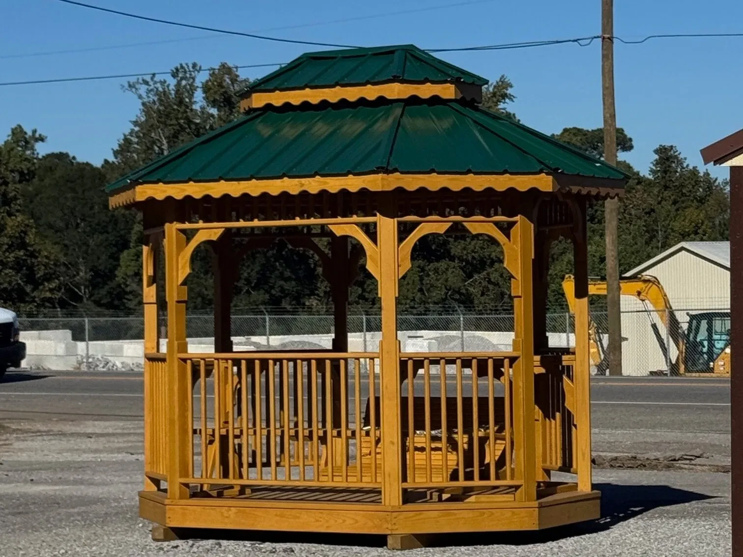 the side view of a wood stained teahouse with posts and railings and a green metal roof
