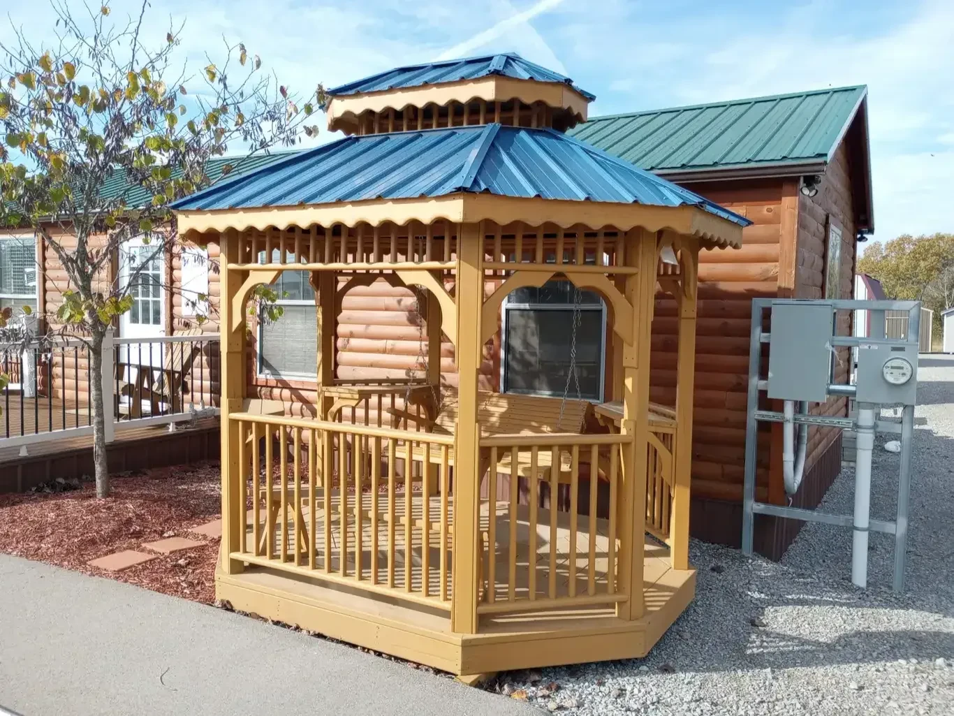 a honey gold color stained wood teahouse with a blue metal roof