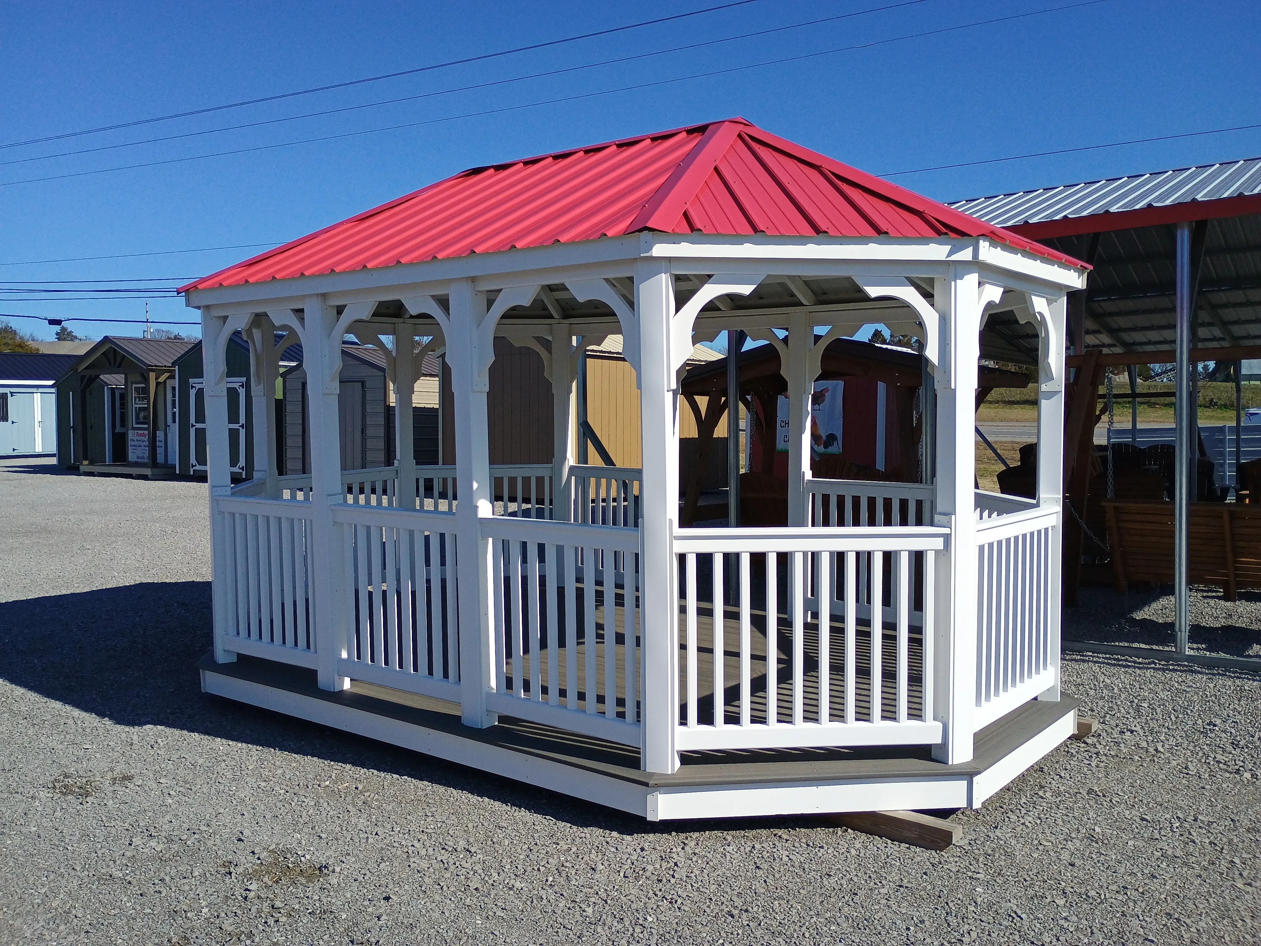 a 10x16 white vinyl gazebo. It has an opening to walk through on the long side and has a red metal roof with vertical metal