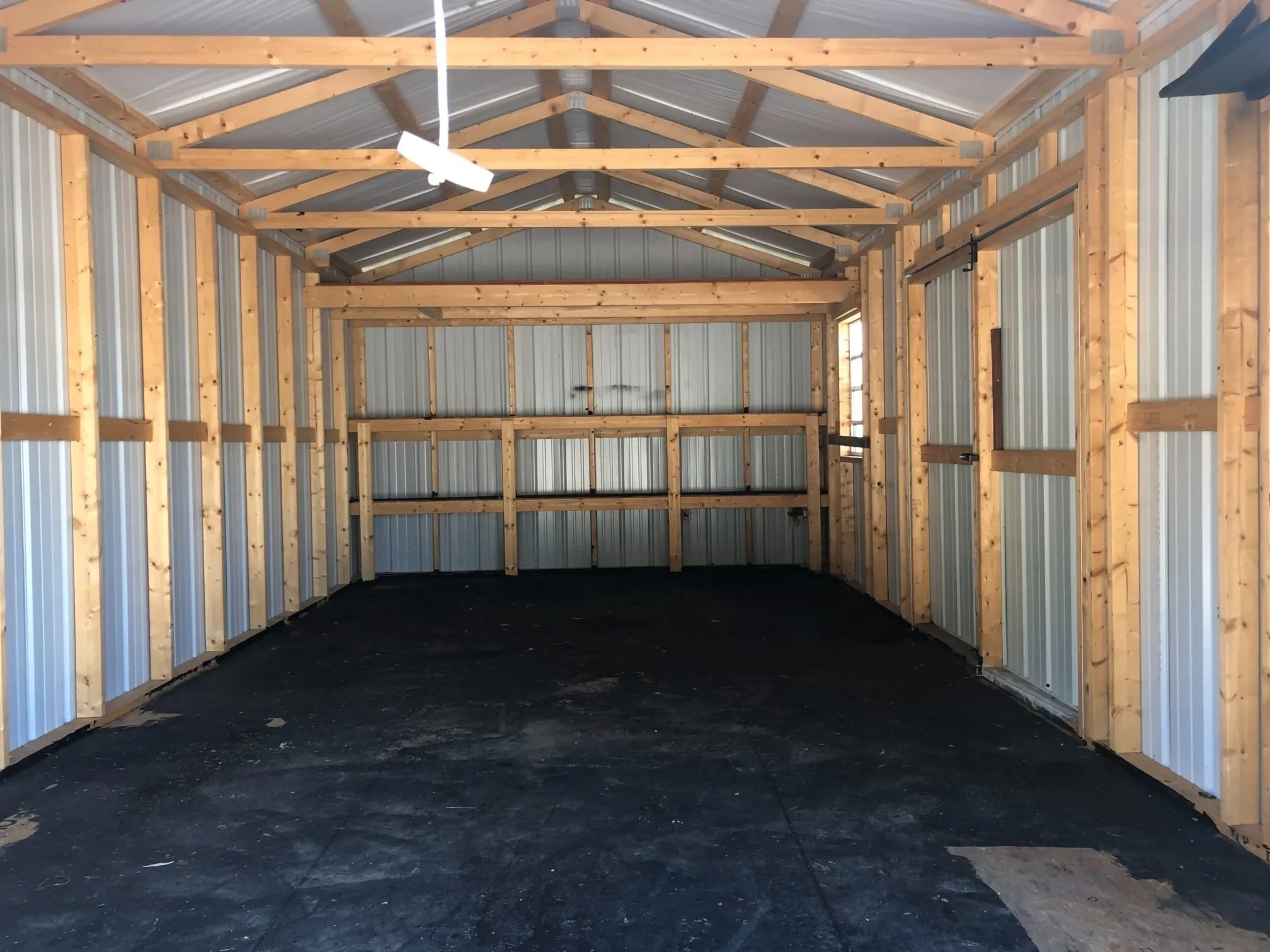 A metal shed interior with double shelves, a loft, and painted black floor