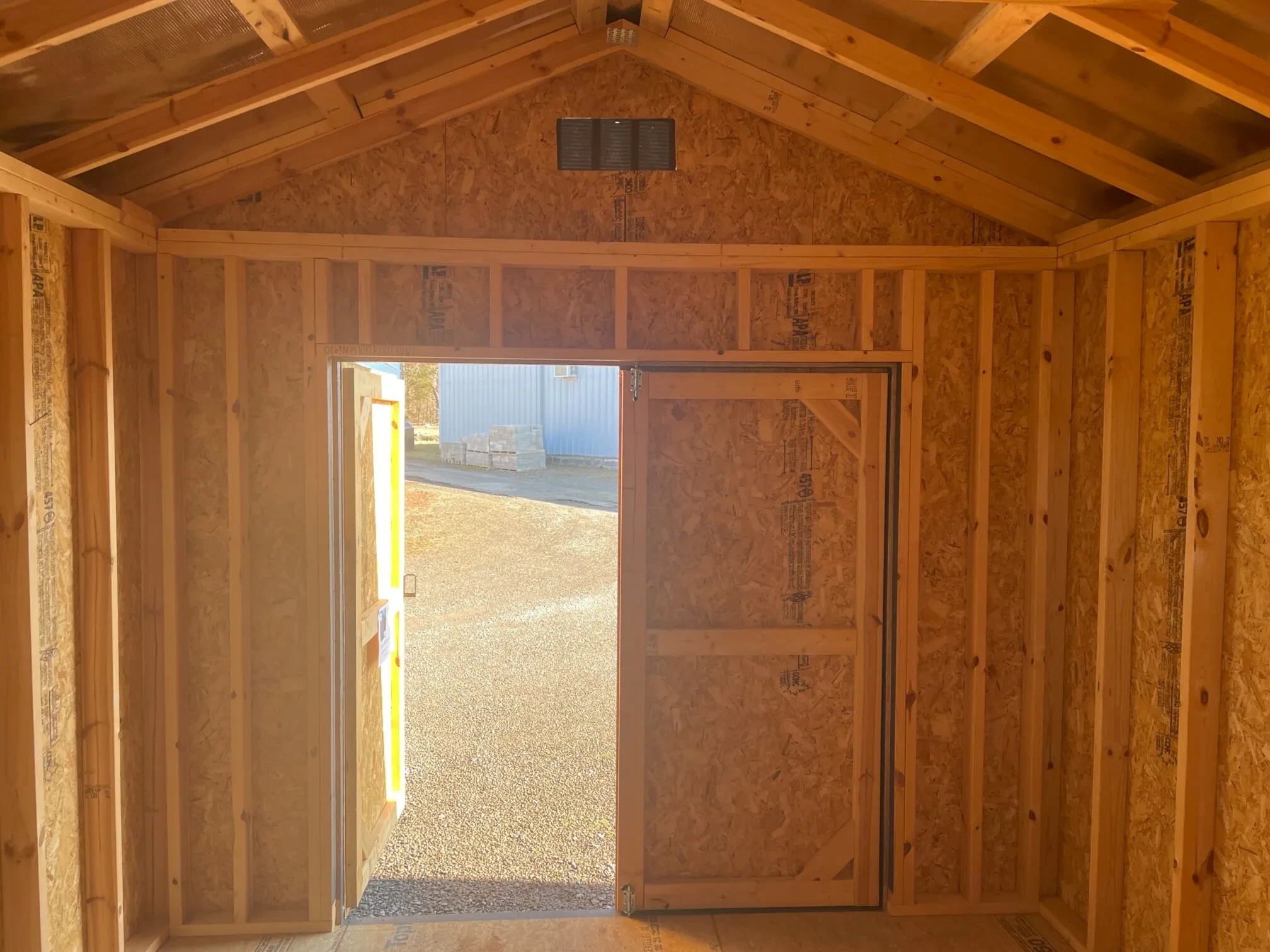 inside a wood utility shed looking at the double doors, the left door is open