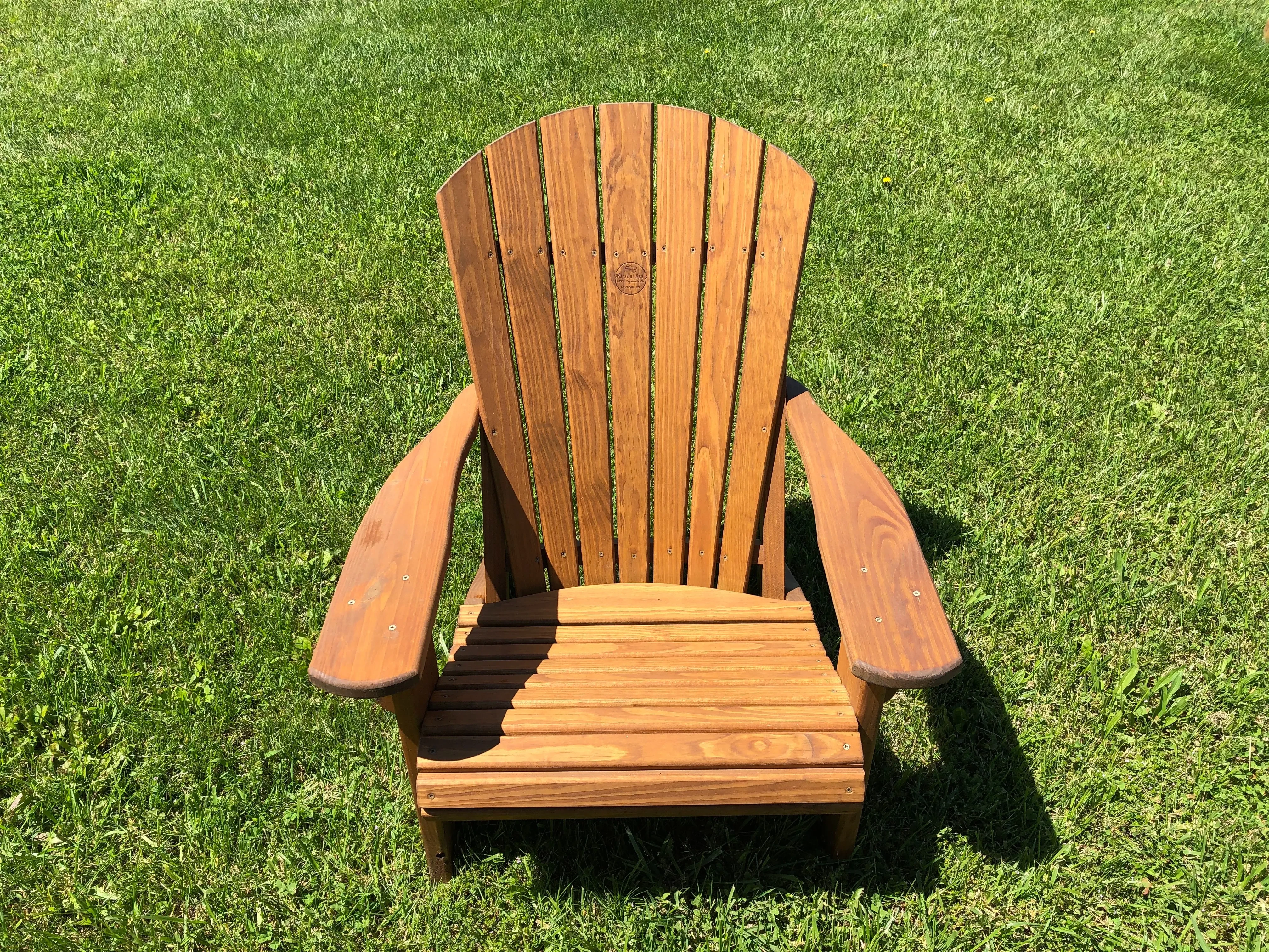 Wood adirondack chair in the grass.